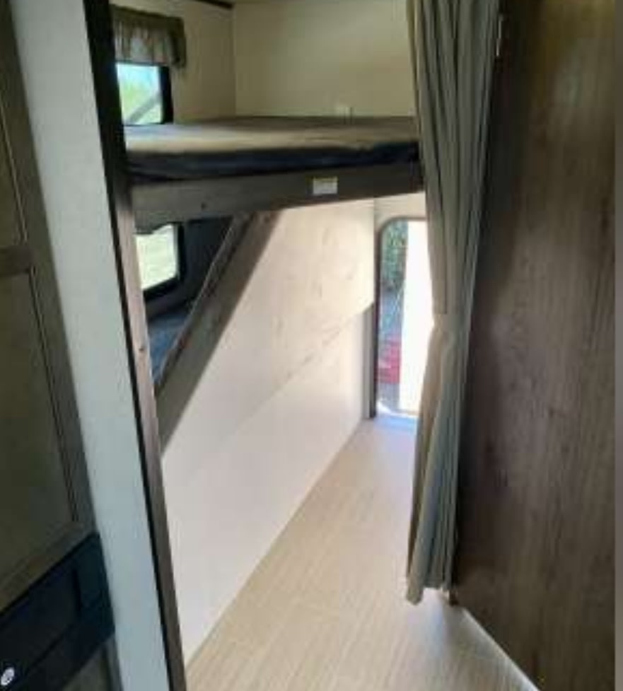 RV rental interior featuring cozy bunk beds and a narrow hallway, providing compact living space.. Keystone RV Passport SL 2021