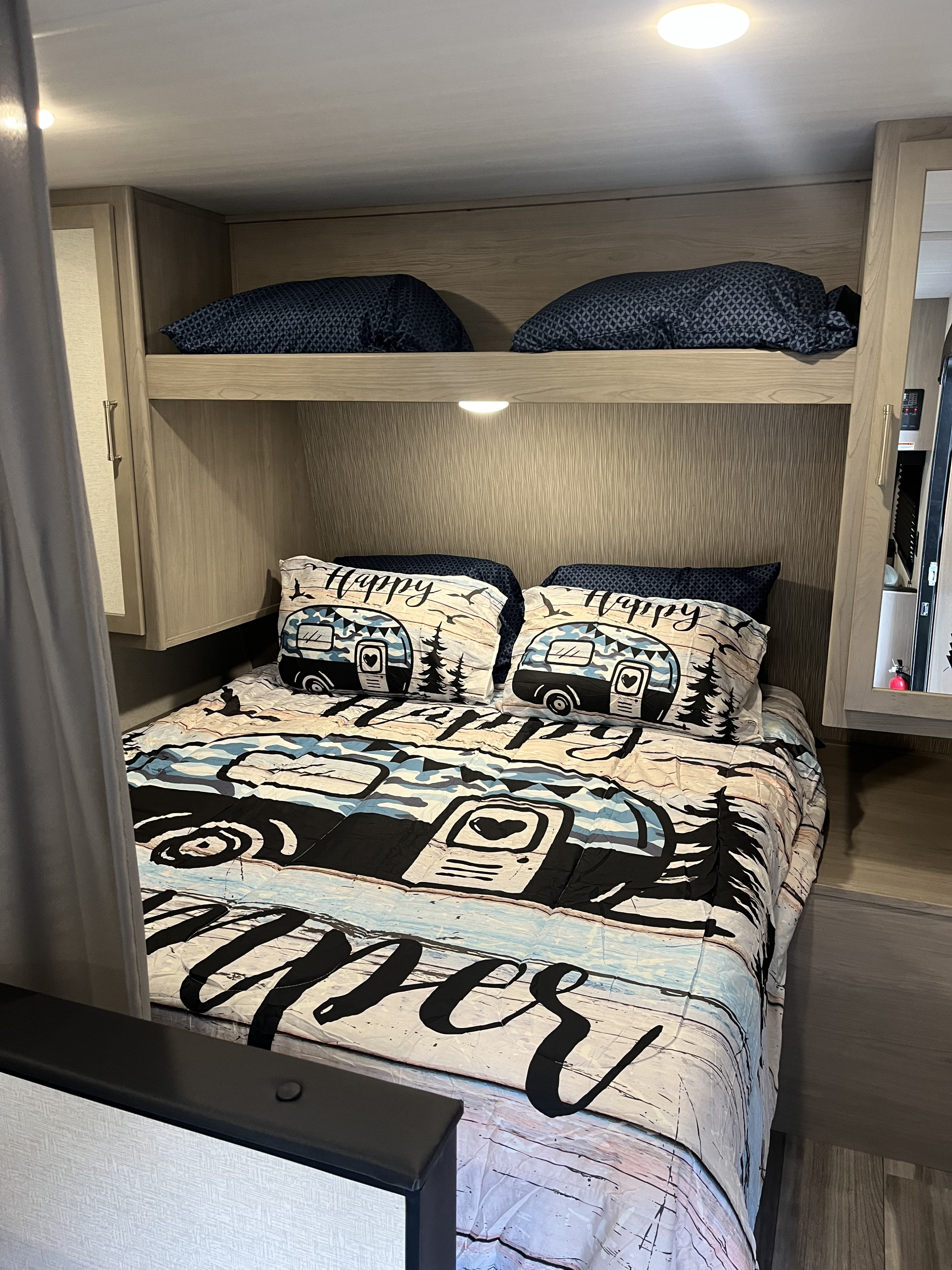 Cozy RV rental bunk beds with vibrant 'Happy Camper' bedding.. Keystone RV Springdale 2024