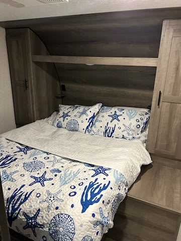 Relax in this RV rental's cozy bedroom featuring blue nautical bedding, ample storage, and a comfortable bed.. KZ Sportsmen 2021