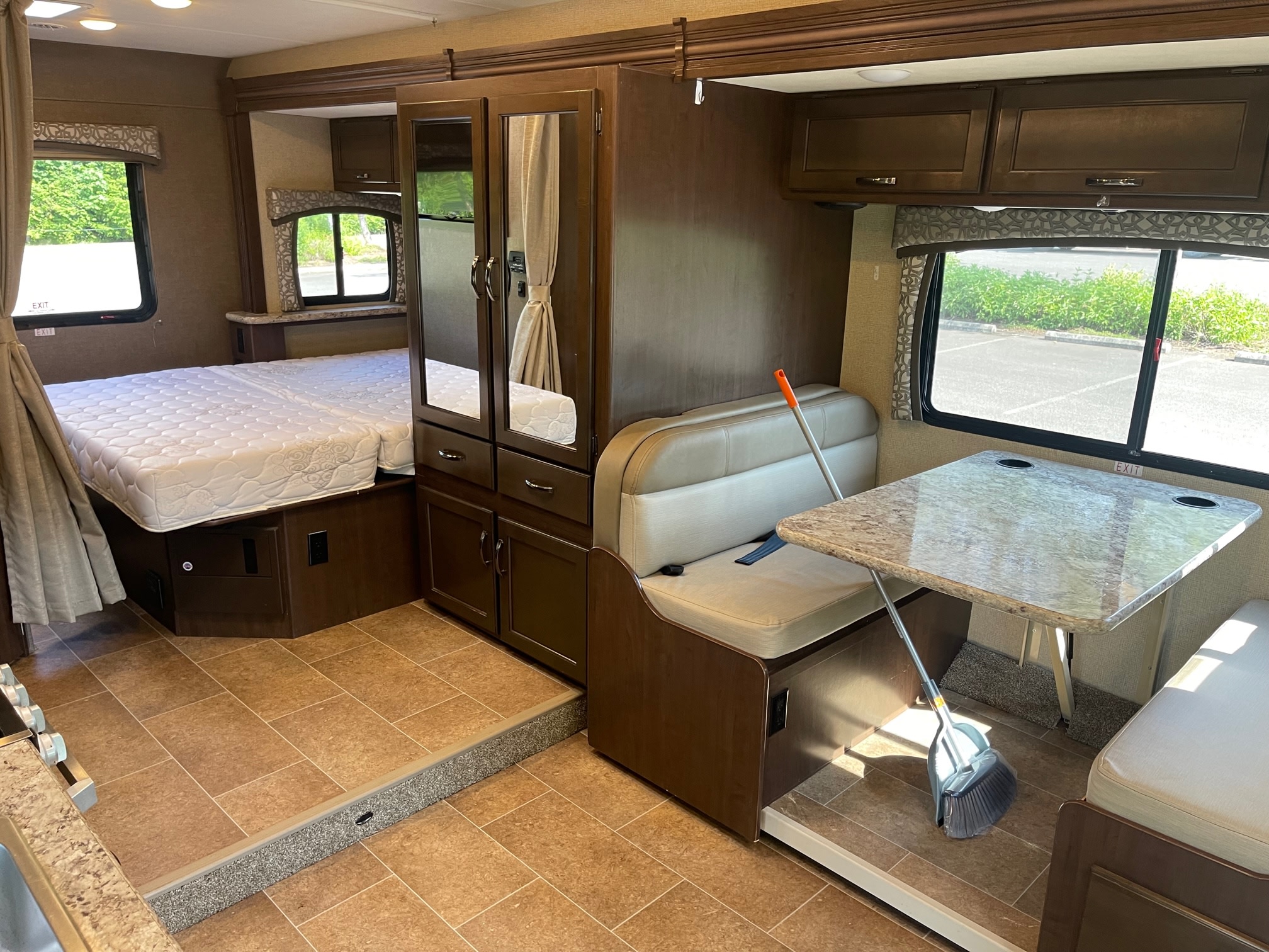 RV rental interior view: clean bedroom area with mattress, mirrored wardrobe, and compact dinette with table.. Thor Chateau 2019
