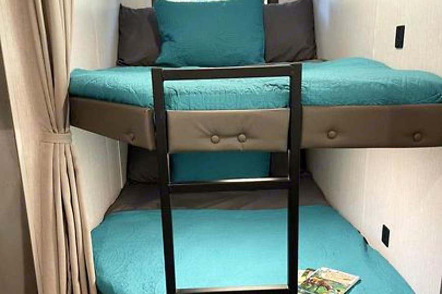 RV rental bunk beds: Space-saving design with teal bedding and a ladder for comfortable sleeping.. Forest River Salem Cruise Lite 2023
