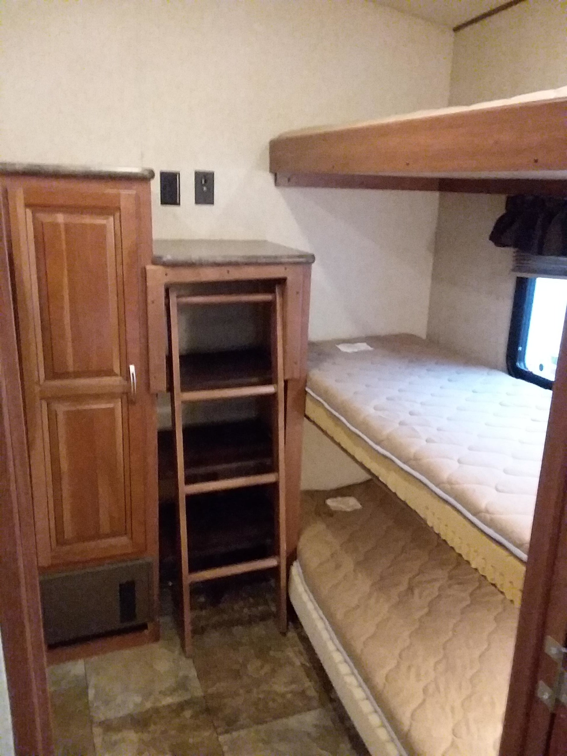 Compact RV rental interior featuring bunk beds, a storage cabinet, and a window.. Forest River Wildcat Extralite 2013