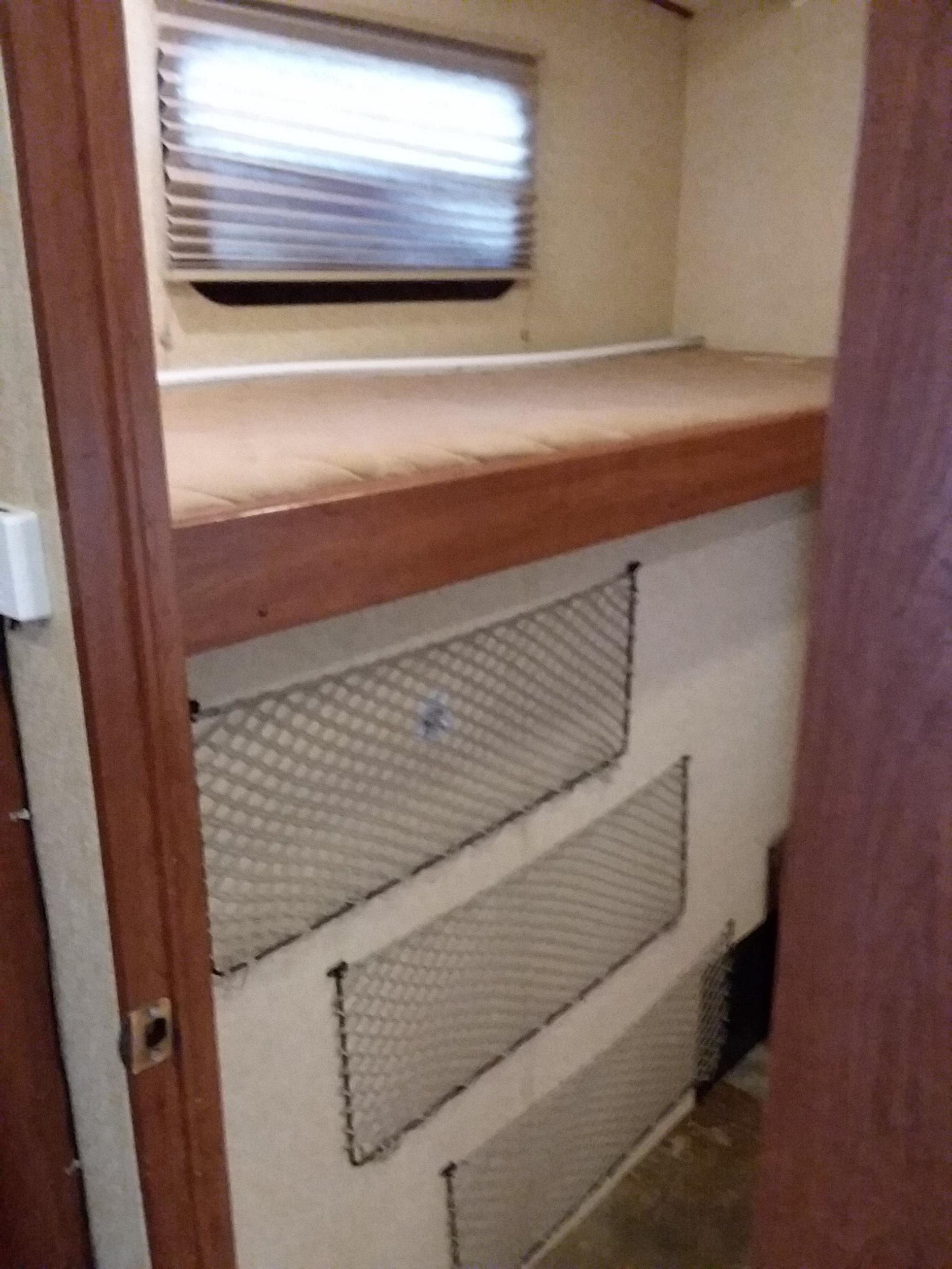 RV rental bunk bed with window above, plus mesh storage nets below, for compact living.. Forest River Wildcat Extralite 2013