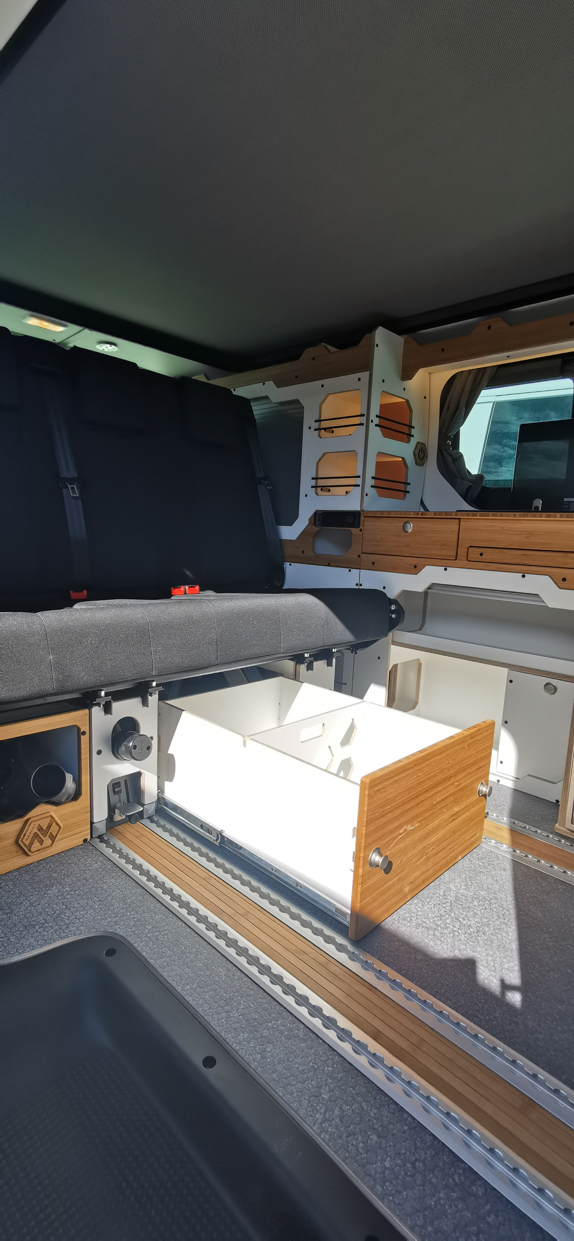 Spacious RV rental interior with custom cabinetry, a black seating area, and an open pull-out storage drawer.. Renault TRAFIC 2024