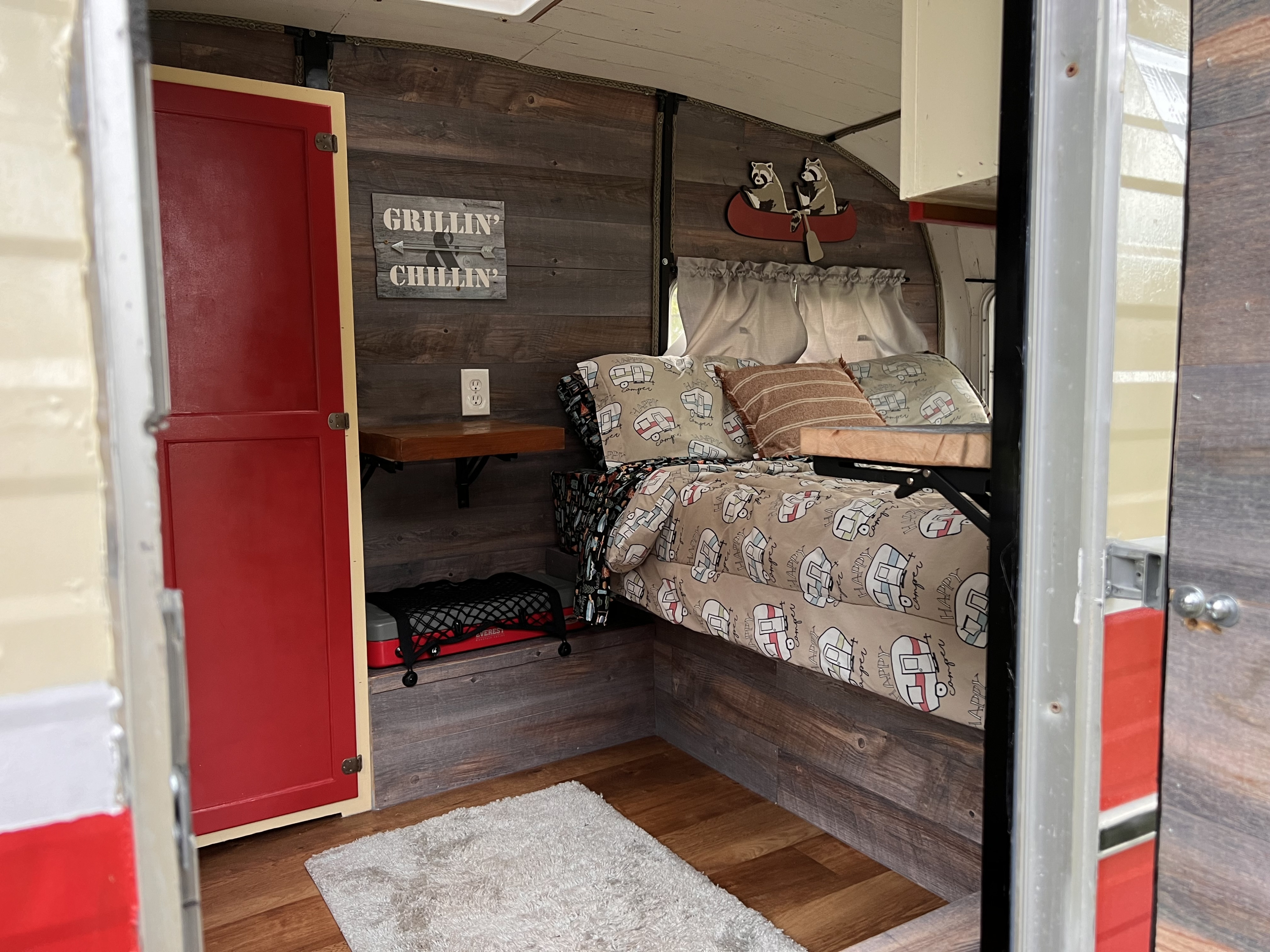 Experience a unique RV rental: wood-paneled interior, "Happy Camper" bed, and playful decor for comfortable glamping.. Shasta Cygnet 1973