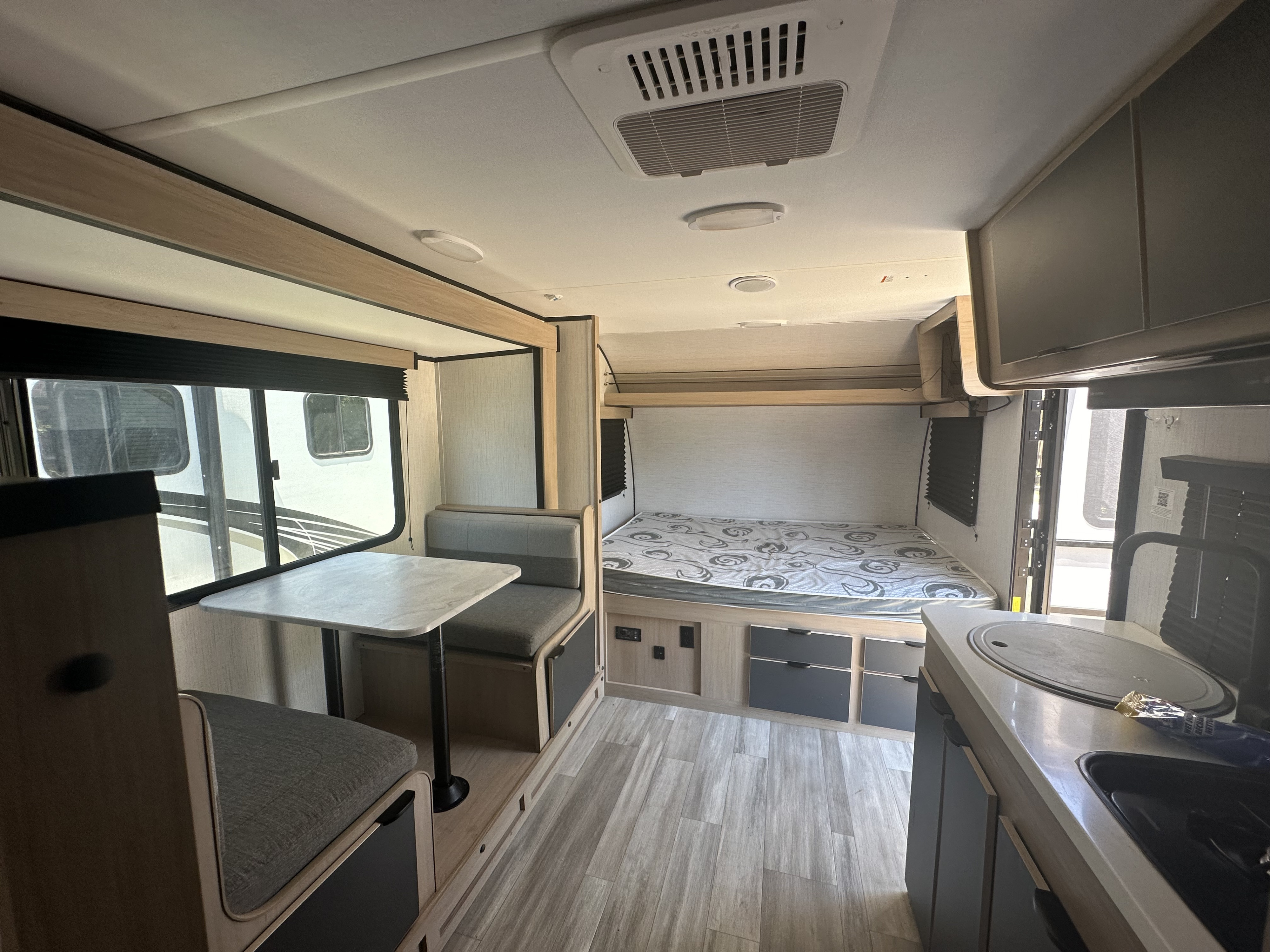Experience a modern RV rental interior featuring a cozy dinette, comfortable bed, and compact kitchen—perfect for mobile living.. Cruiser RV Hitch 2022