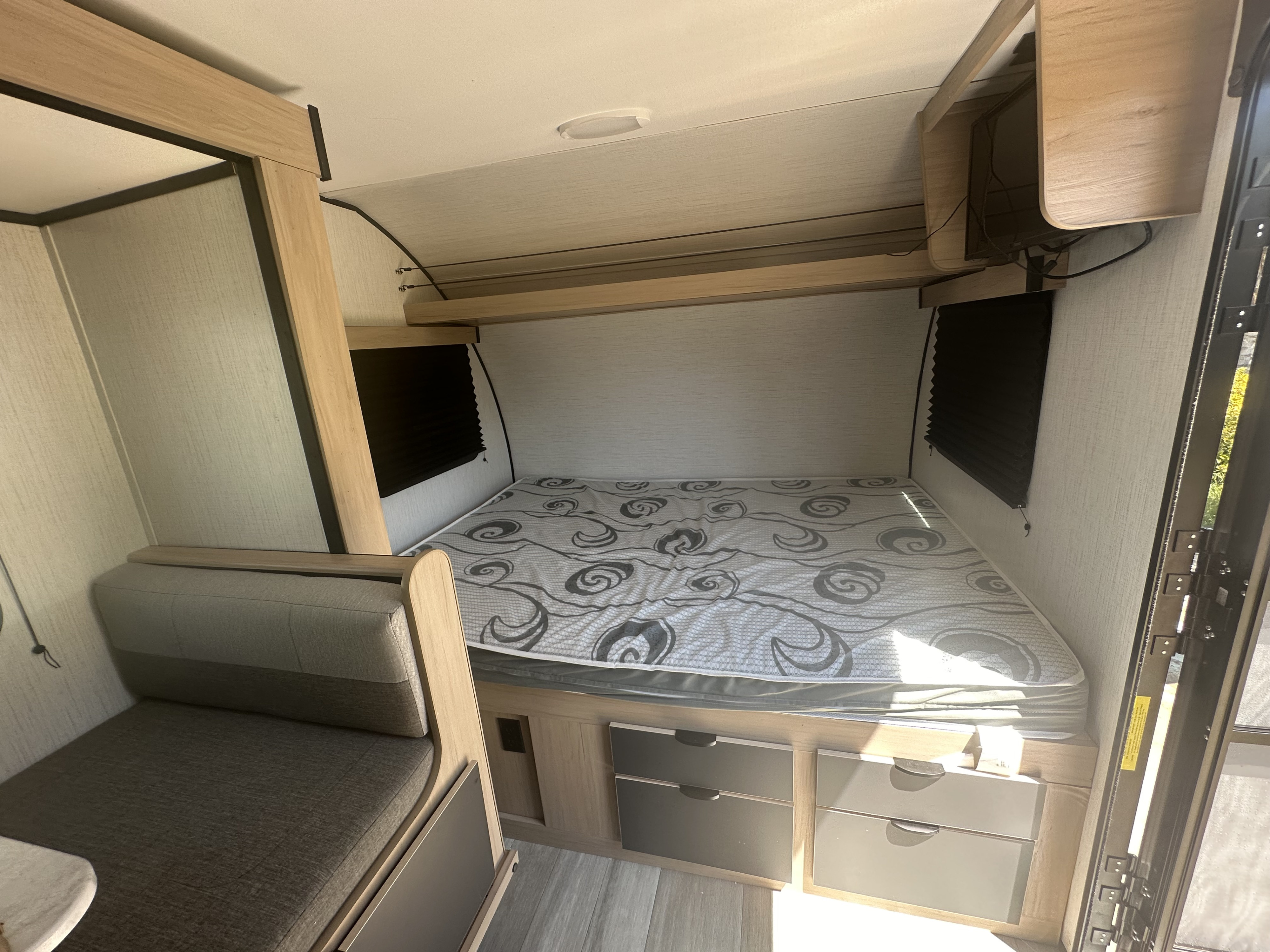 Compact RV rental interior with a cozy bed, dinette, mounted TV, and under-bed storage, perfect for your travel adventures.. Cruiser RV Hitch 2022