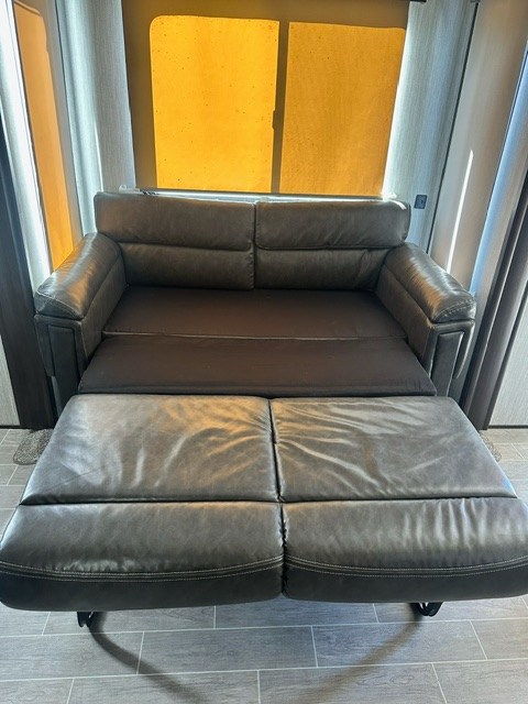 Extended dark leather-look pull-out sofa in an RV rental, offering extra comfort and seating.. Forest River Cherokee Arctic Wolf 2019