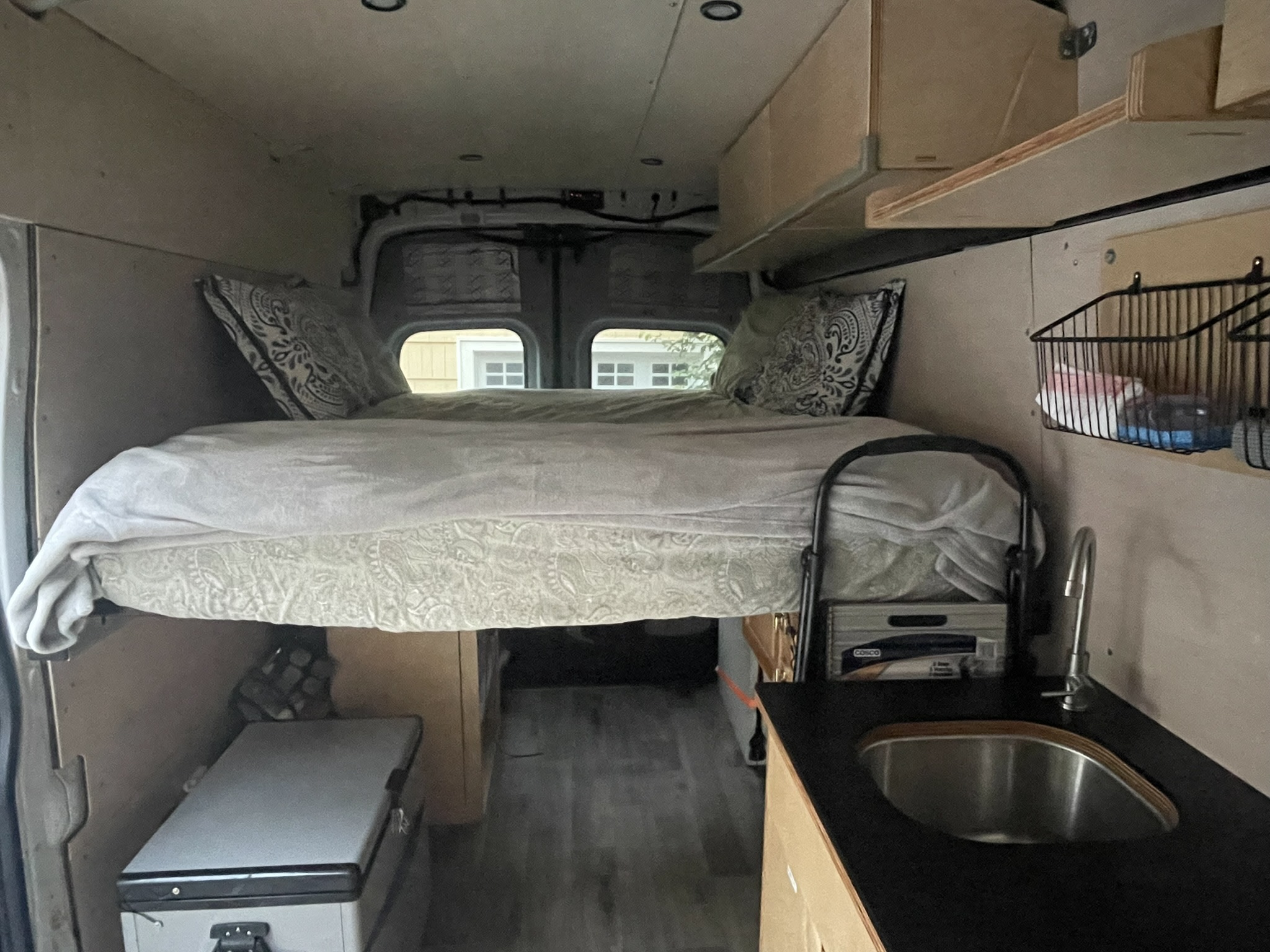 Experience mobile living! This RV rental features a cozy raised bed, compact kitchen with sink, and fridge, ideal for adventures.. Ford Transit 2015