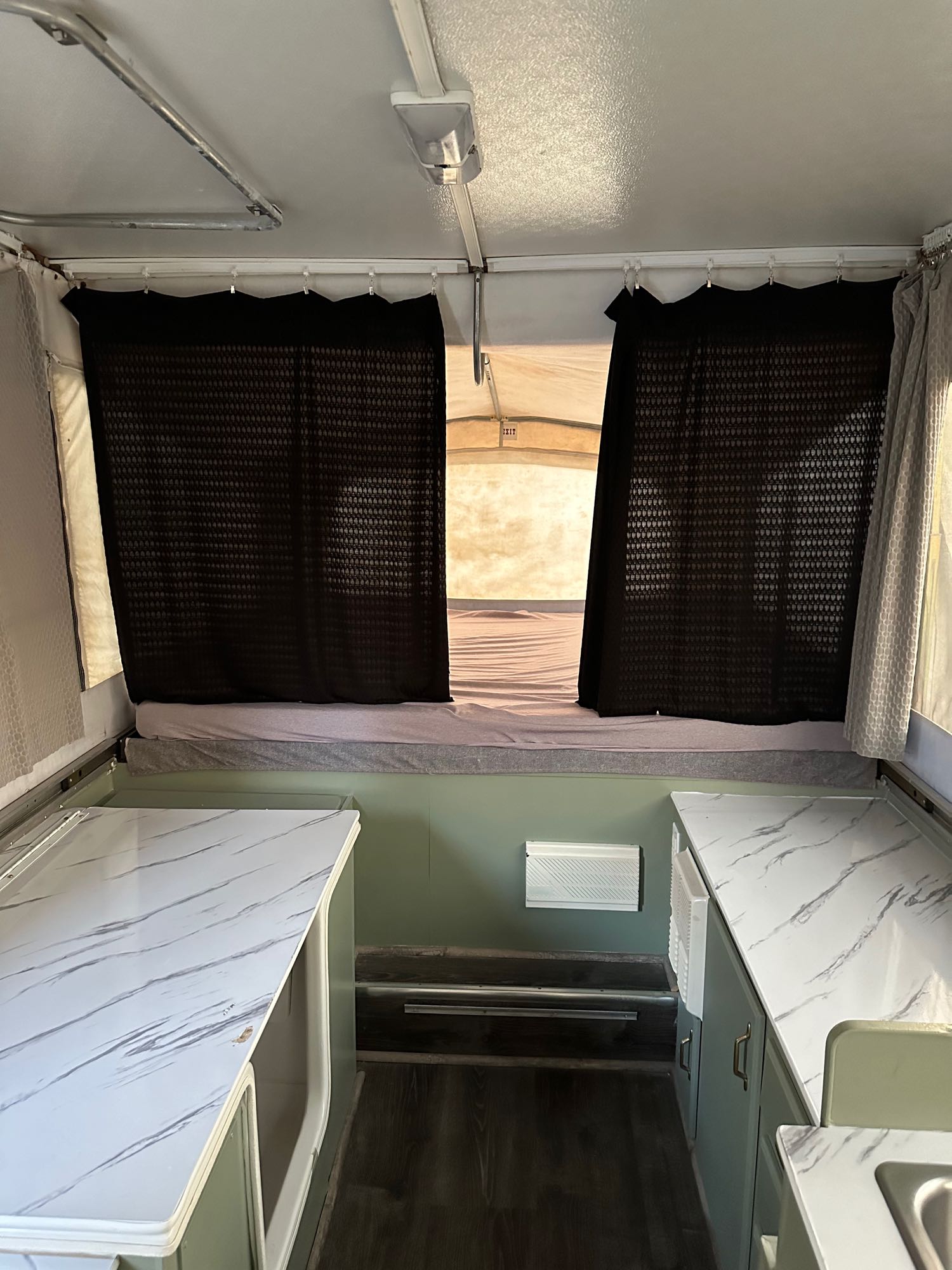 Cozy pop-up RV rental interior with beds, marble counters, and privacy curtains. Great for travel!. Jayco Eagle 2001