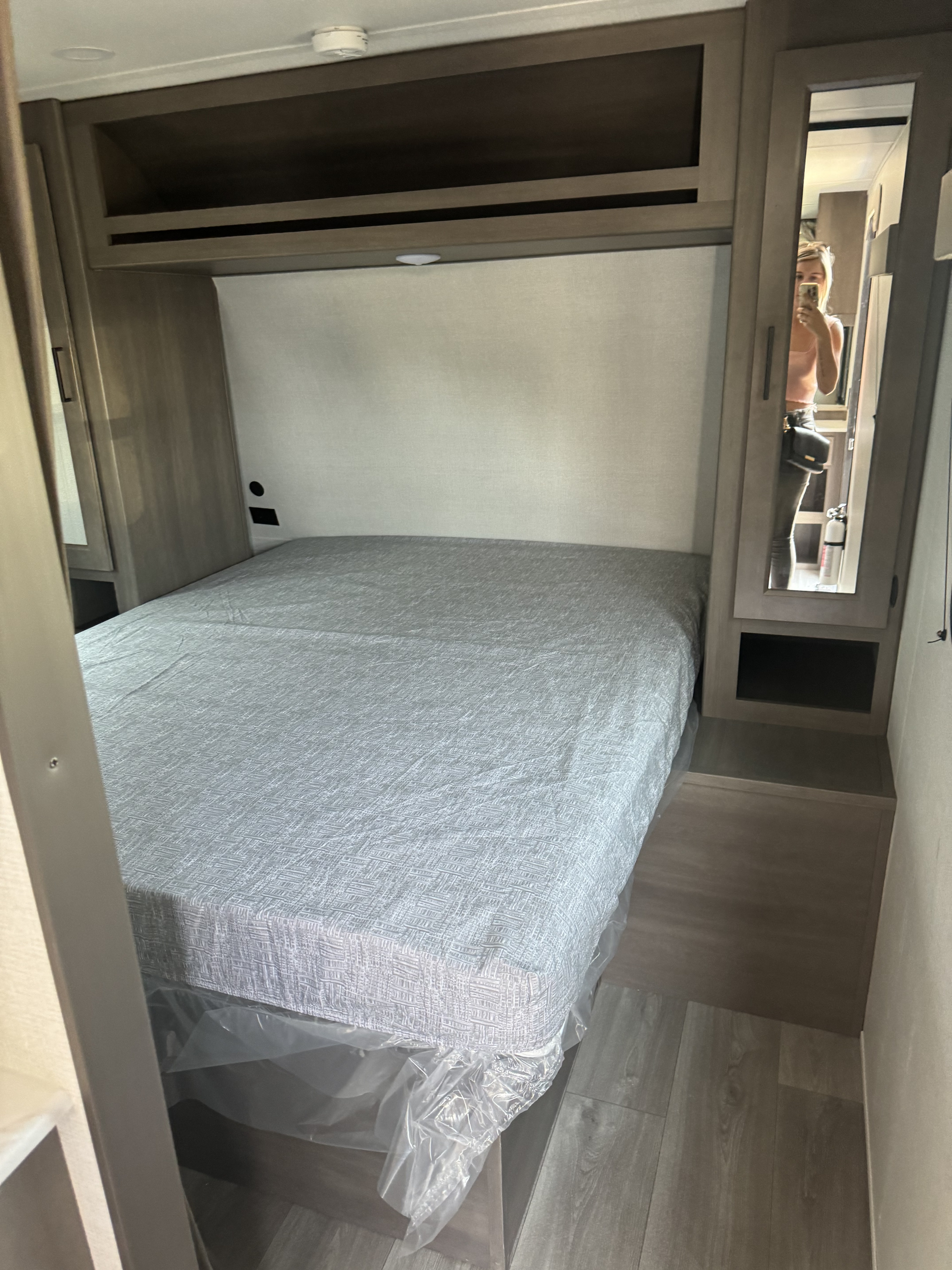RV rental interior: bedroom with a fresh bed, overhead cabinets, and mirrored closet. Ideal for travel.. Grand Design Transcend Xplor 2024