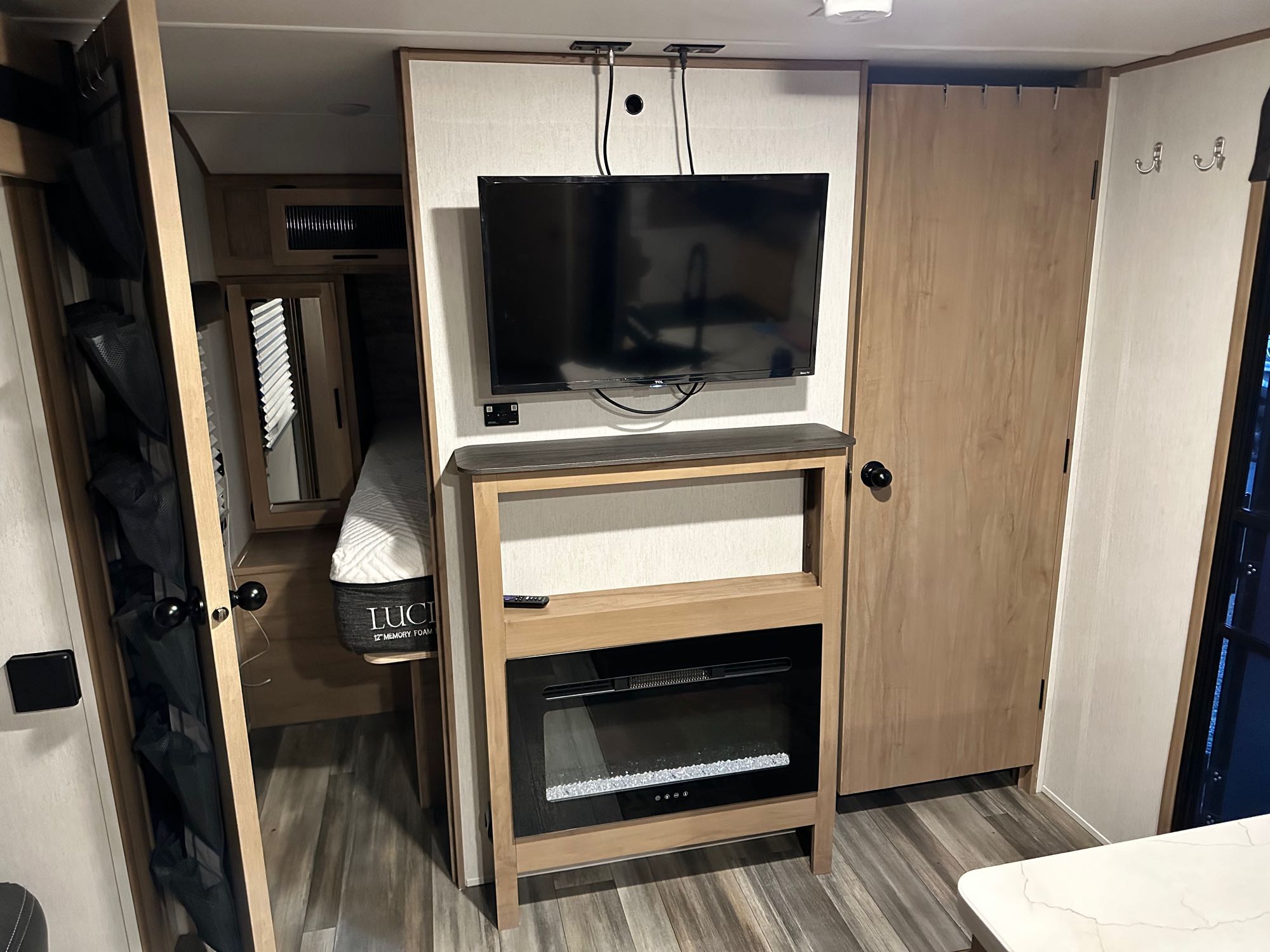 Spacious RV rental living area featuring a wall-mounted TV, electric fireplace, and bedroom access. Modern camper interior.. Forest River Cherokee Alpha Wolf 2023