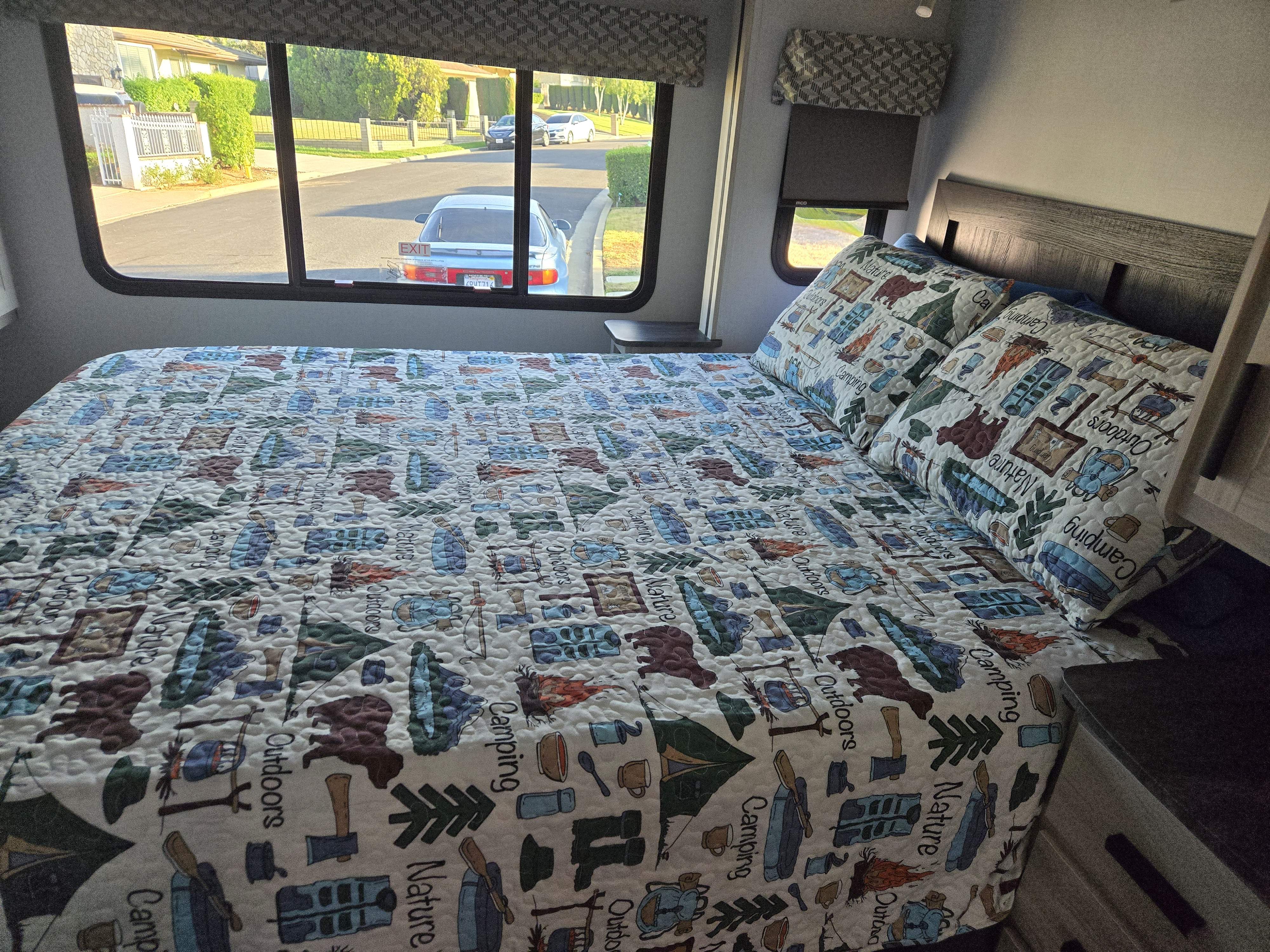 Inviting RV rental bedroom with camping-themed bedding and wide windows for comfortable travel.. Forester Classic 2023