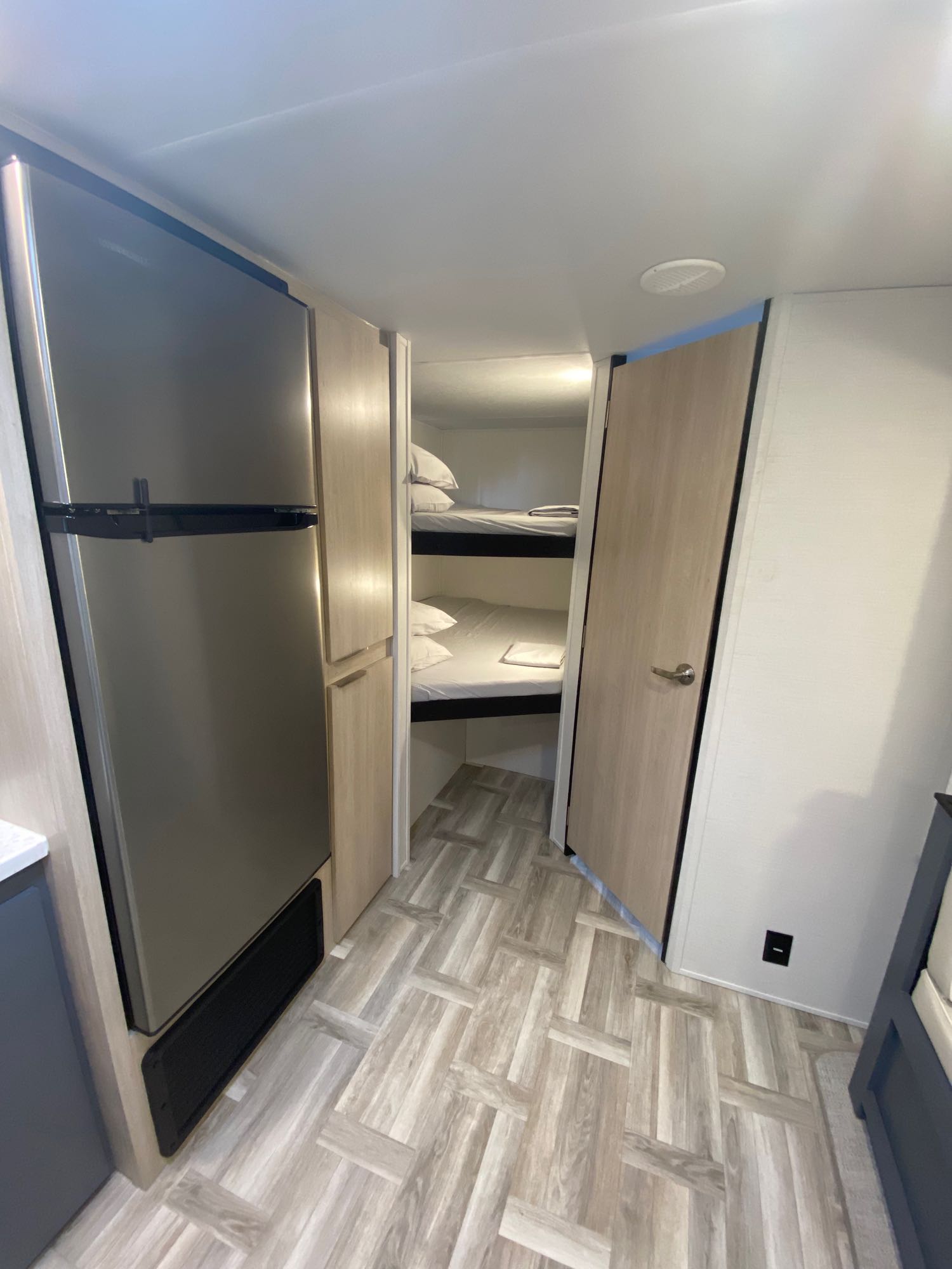 RV rental interior features a large stainless steel fridge, storage cabinets, and cozy bunk beds, ideal for family travel.. Prime Time 270BHSLE 2024