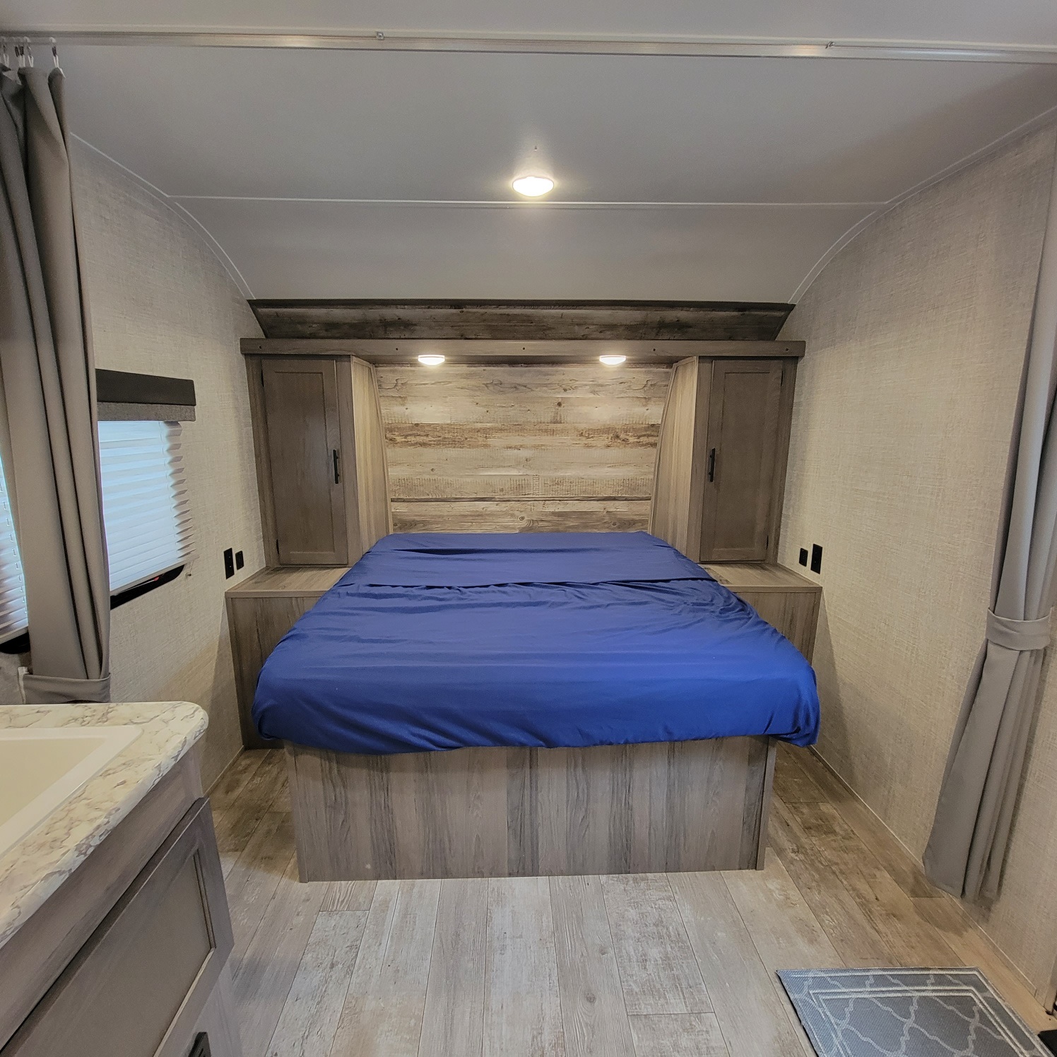 Cozy rv rental bedroom featuring a blue bed, built-in storage, and wood-paneled walls. Perfect for your next adventure.. Gulf Stream Kingsport 2020