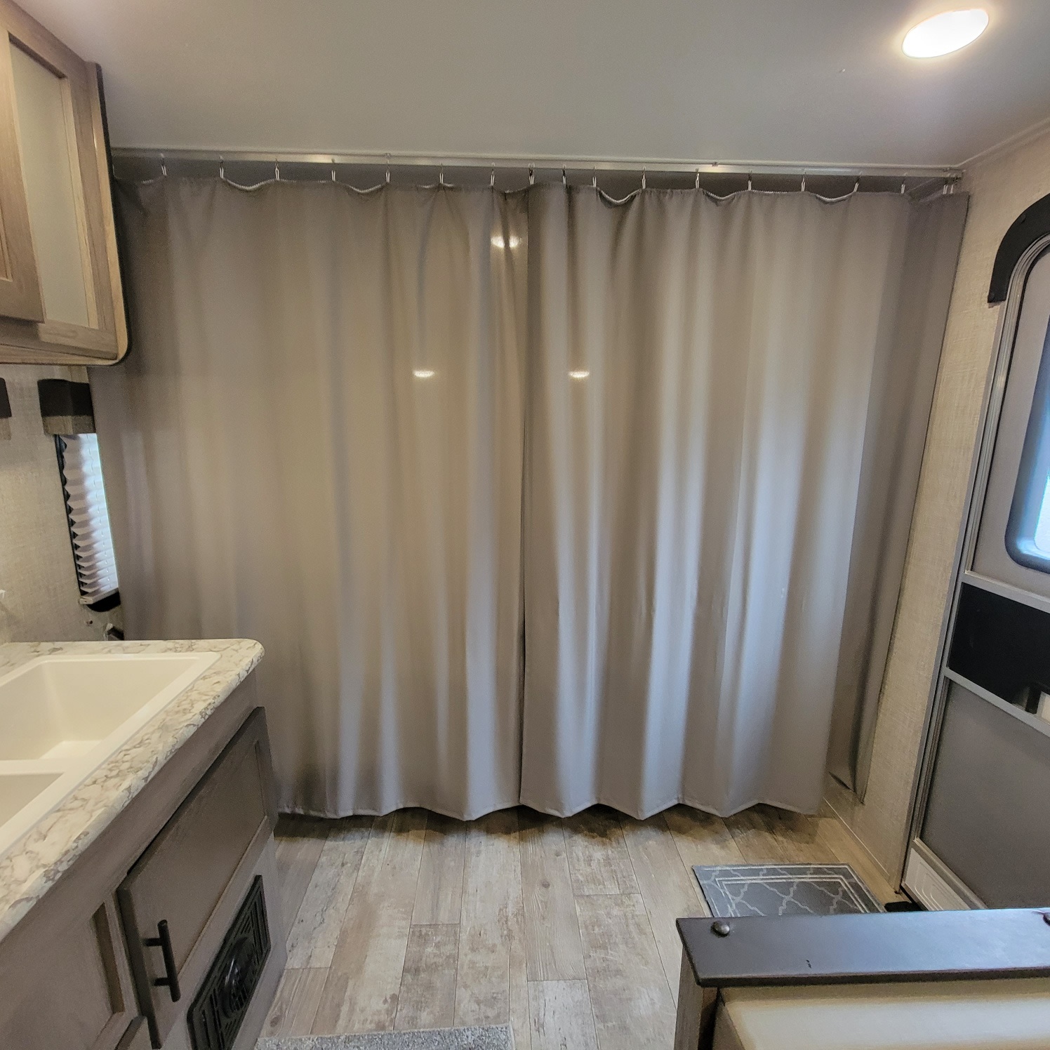 Inside an RV rental: light gray curtains for privacy, a sink counter, and wood-look flooring create a functional, compact space.. Gulf Stream Kingsport 2020