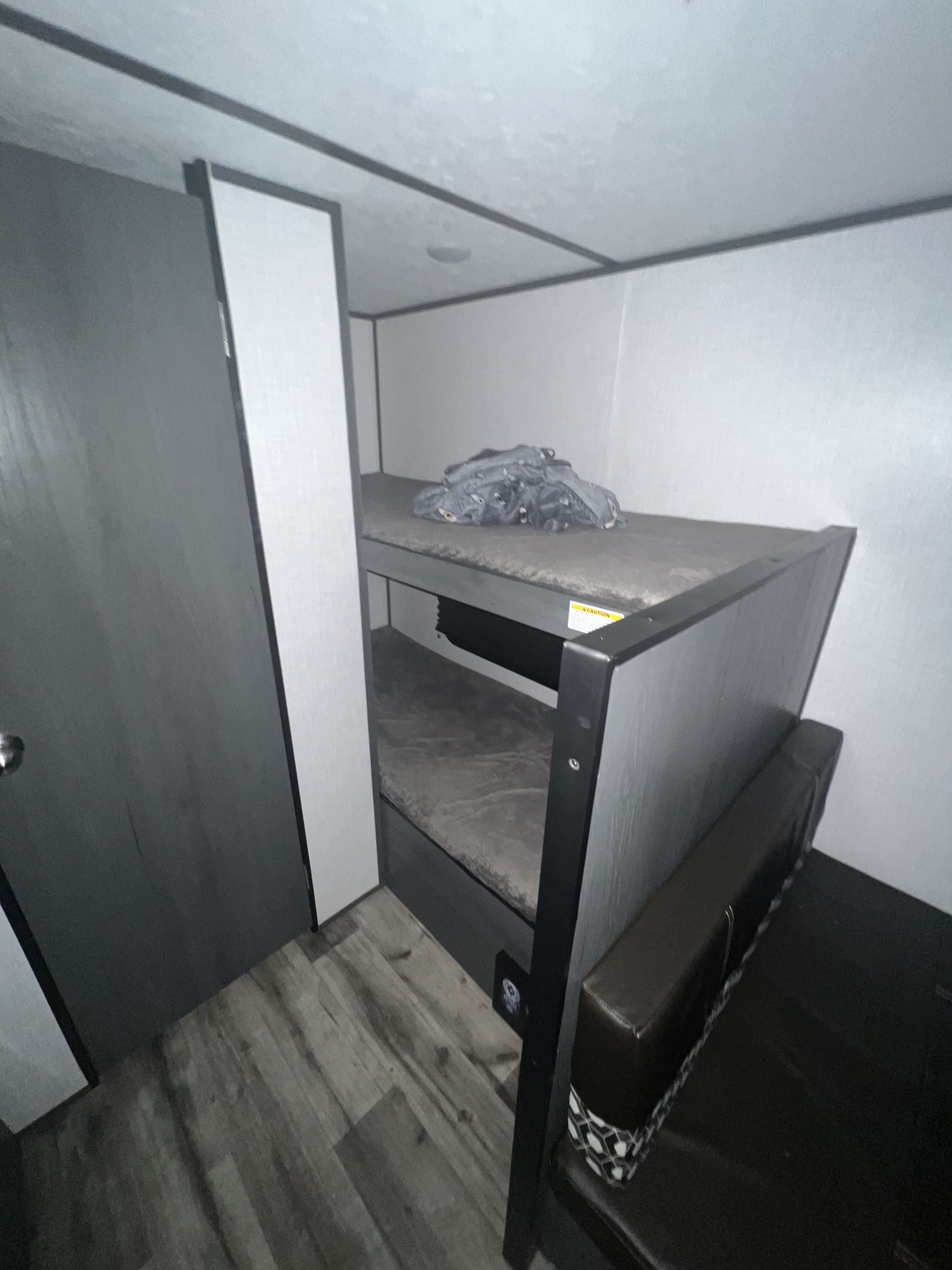 RV rental interior: practical bunk beds, a wardrobe, and a padded bench, maximizing space for travelers.. Dutchmen Aspen Trail 2022