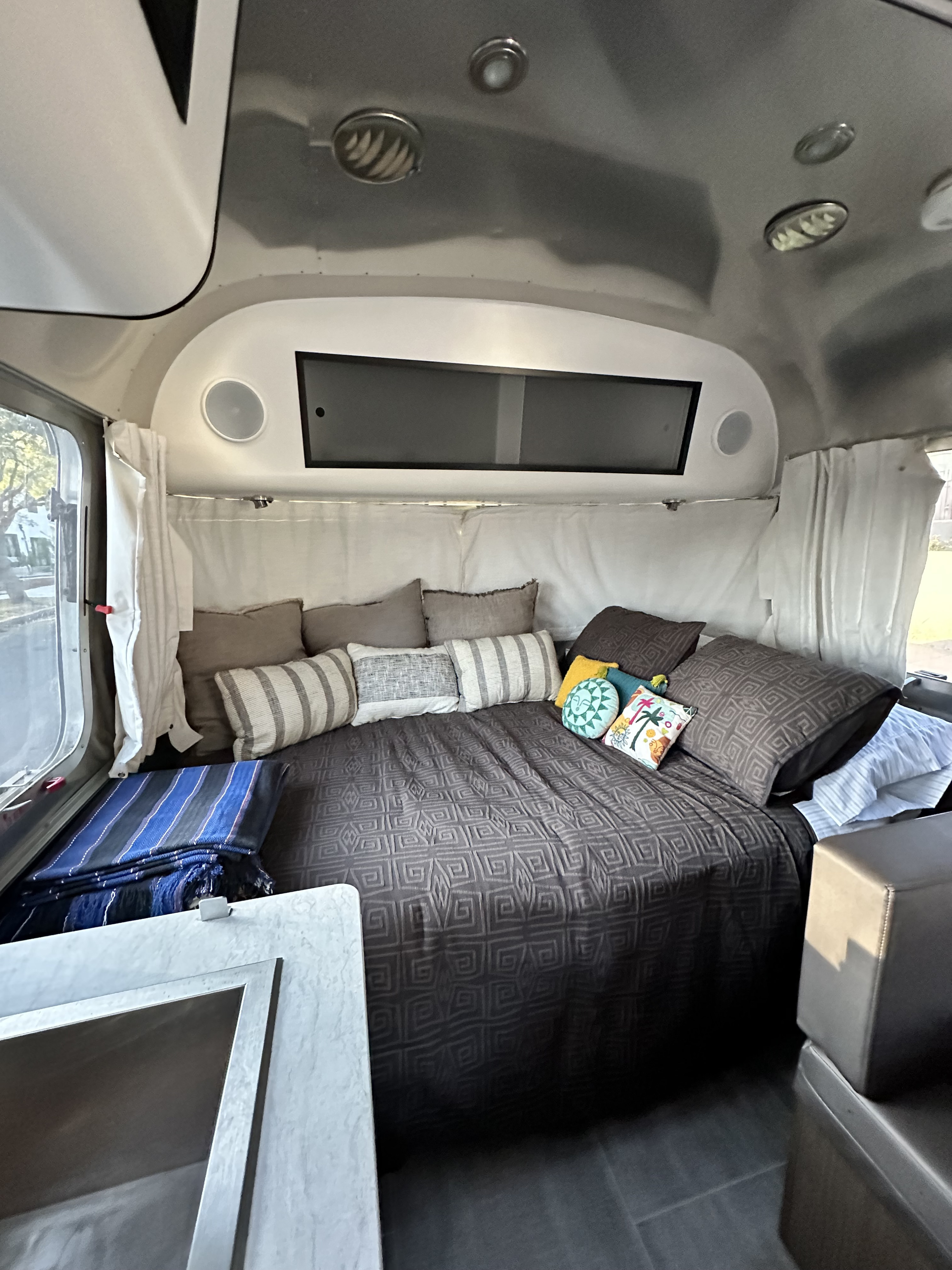 A cozy rv rental interior, showcasing a bed with geometric patterned bedding & colorful pillows.. Airstream Caraval 2021