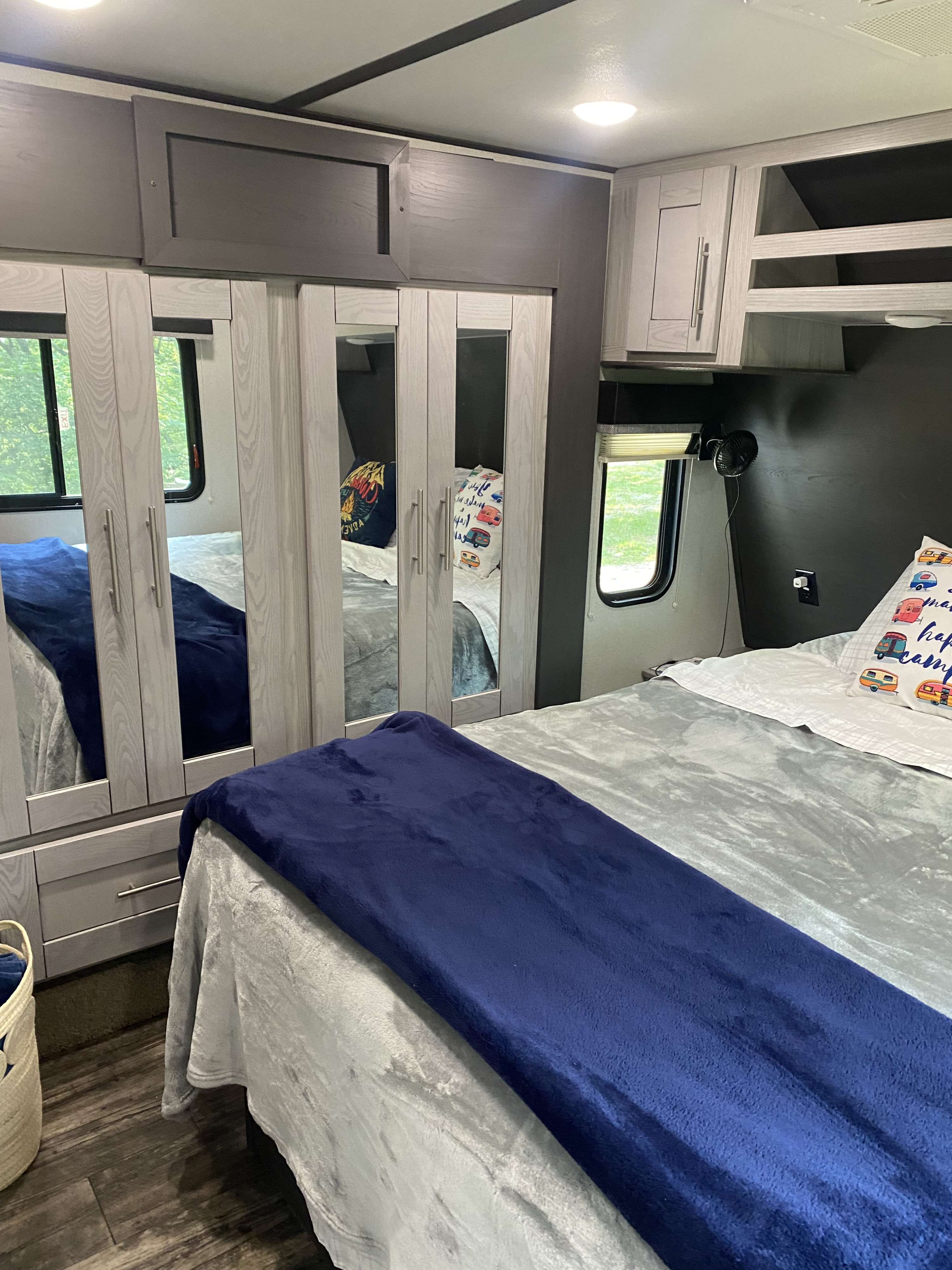 Spacious RV rental bedroom showing a comfortable bed with plush blankets, mirrored wardrobe, and ample overhead storage.. Keystone RV Fuzion Impact Toy Hauler 2021
