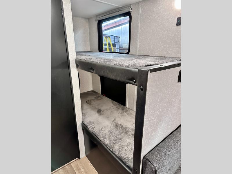 This RV rental offers comfortable bunk beds, perfect for family adventures. The interior features textured walls and a window.. Forest River Cherokee Wolf Pup 2022