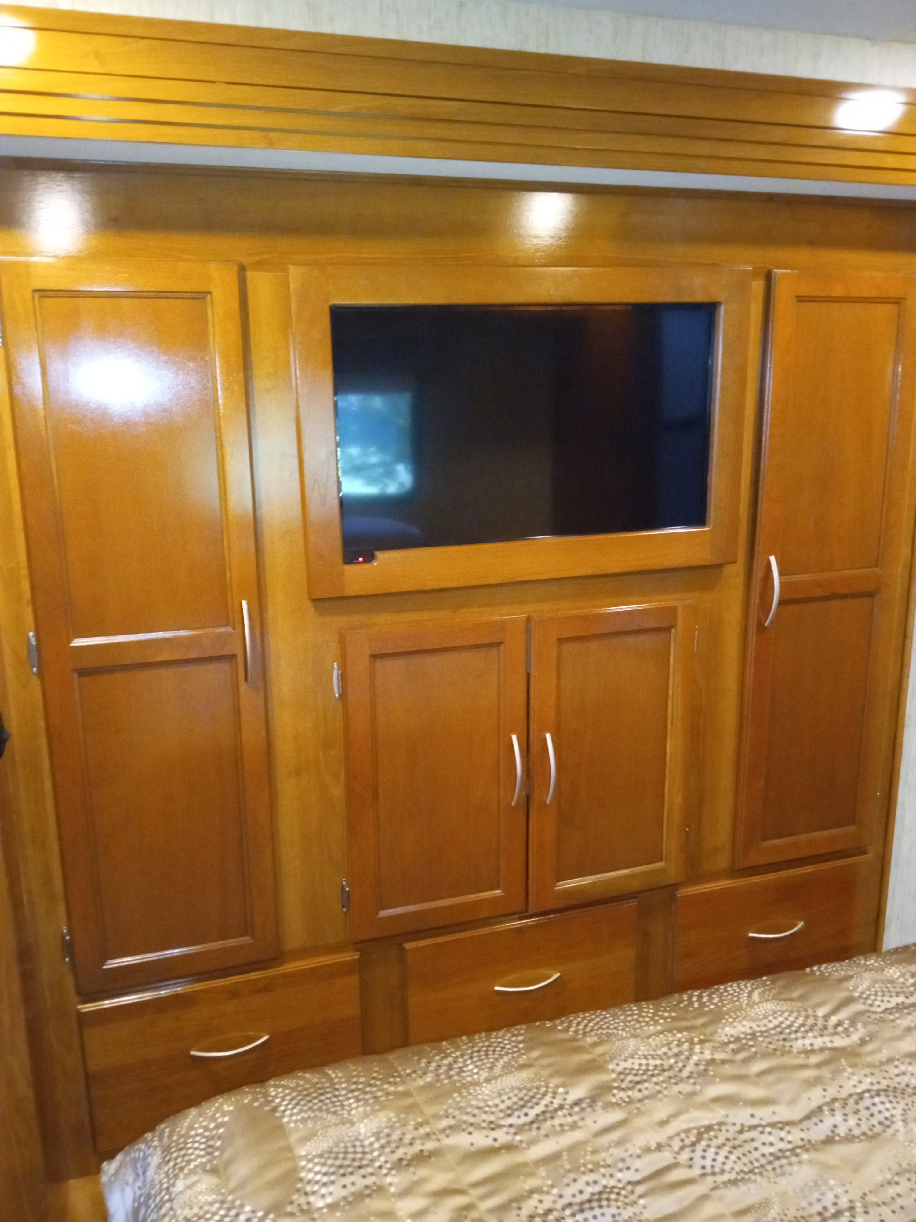 Spacious RV rental bedroom with wood cabinets, built-in TV, and a comfortable bed.. Forest River Coachmen Mirada 2018