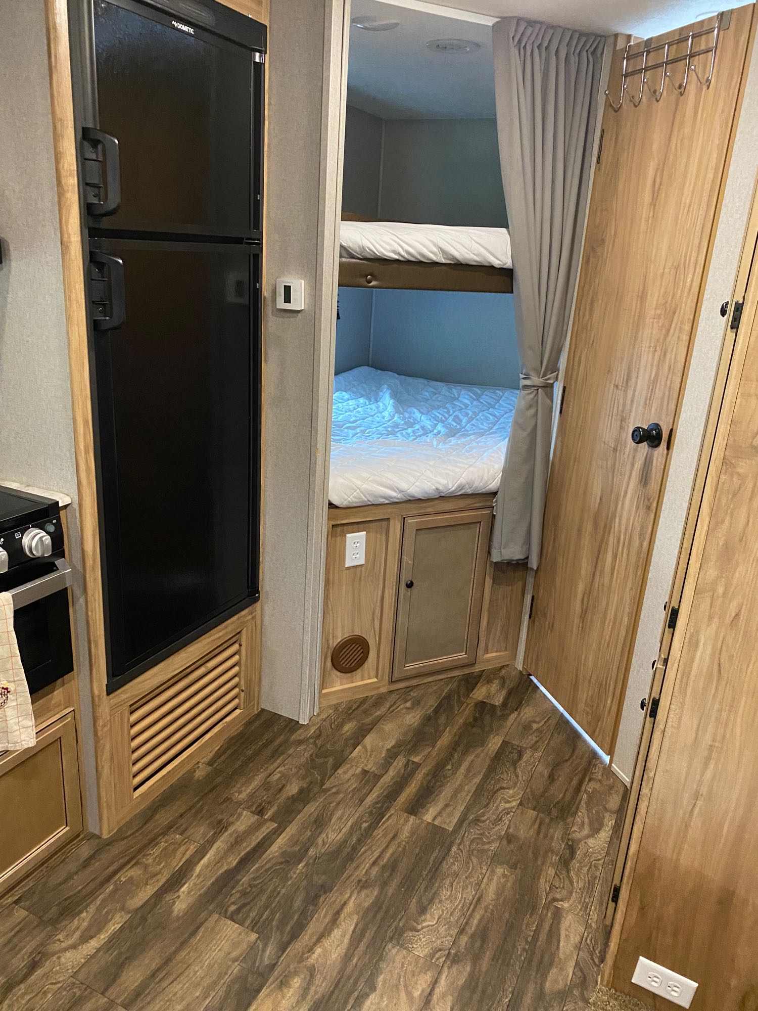 Compact RV rental interior featuring a refrigerator, kitchen area, and bunk beds with a privacy curtain.. Coachmen Freedom Express 2018