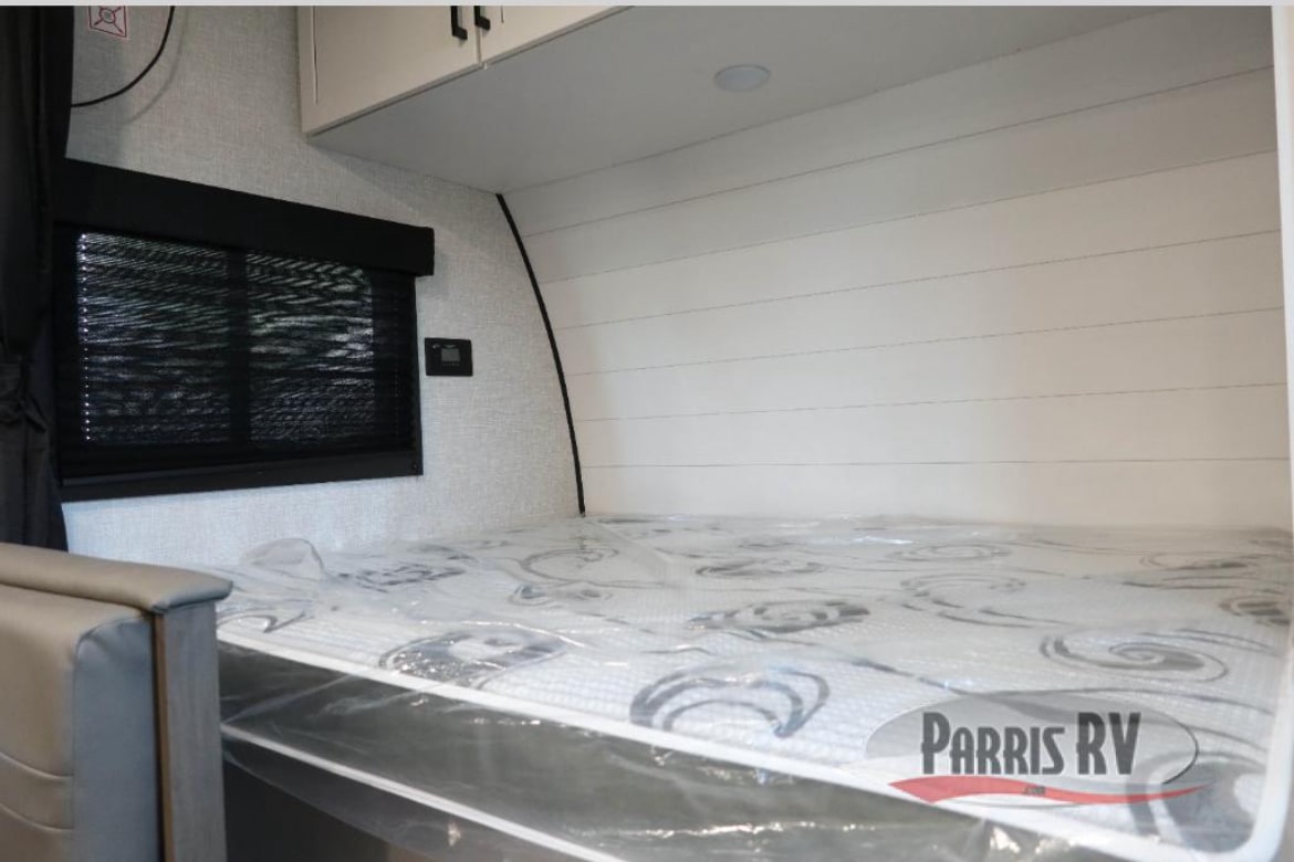 Inside an RV rental: Fresh bed with plastic, window blind, and modern shiplap wall design, ready for adventure.. Highland Ridge Open Range 2025