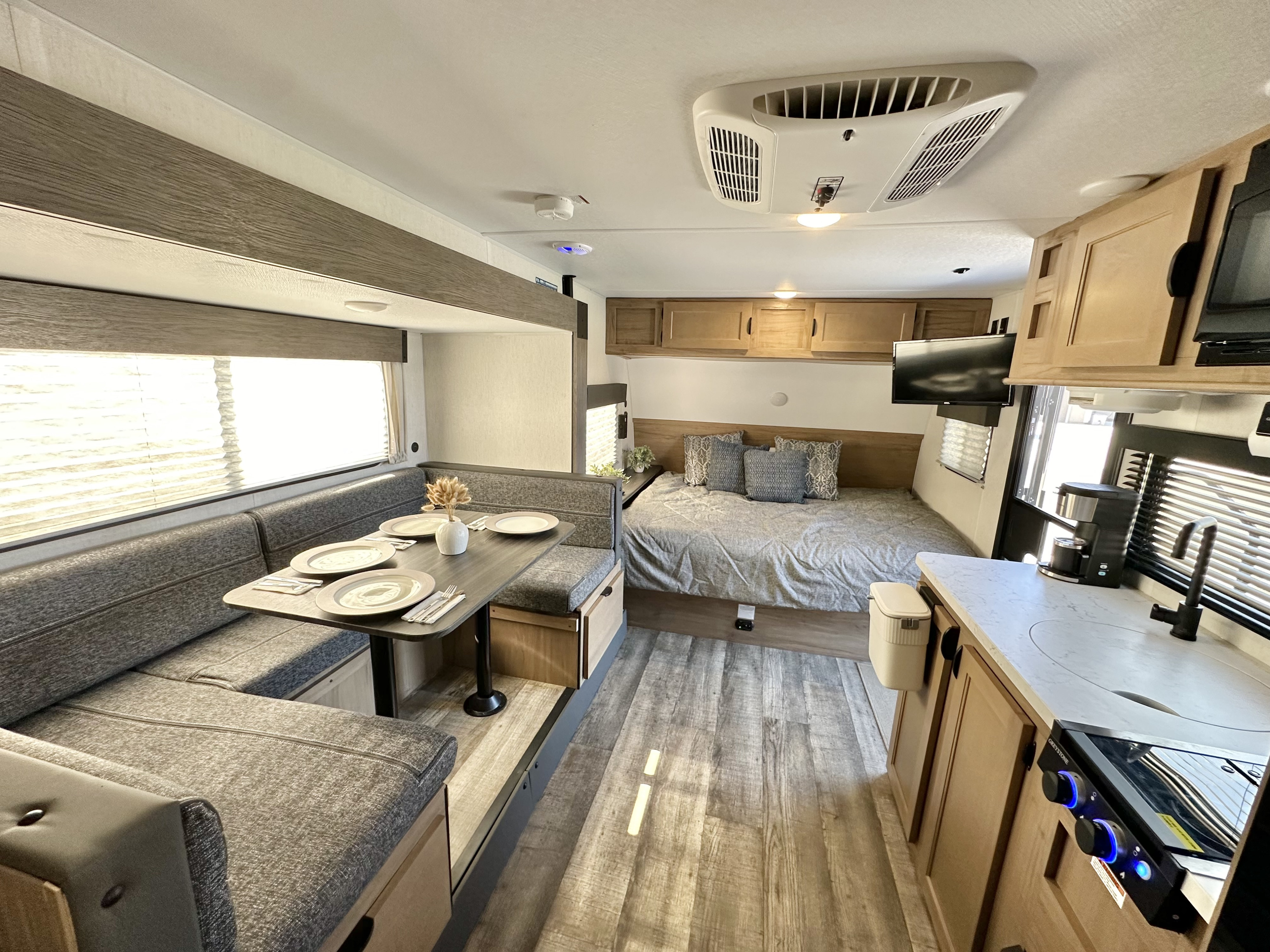 Modern rv rental interior with gray dinette seating, comfortable bed, and compact kitchen.. Forest River Cherokee Wolf Pup 2024