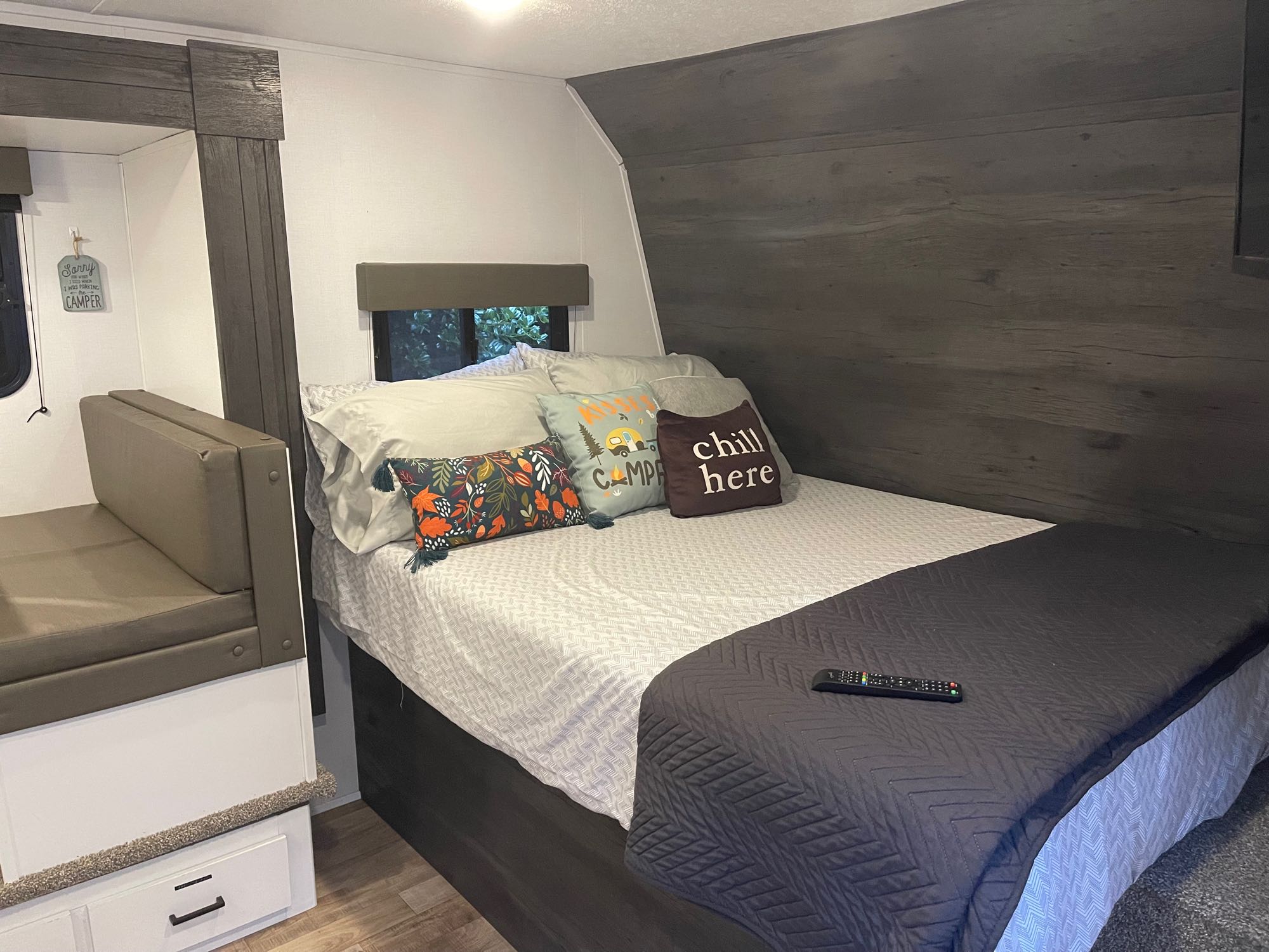 Relaxing RV rental bedroom features a comfy bed with decorative pillows and built-in dinette seating for a cozy stay.. Keystone RV Hideout 2021