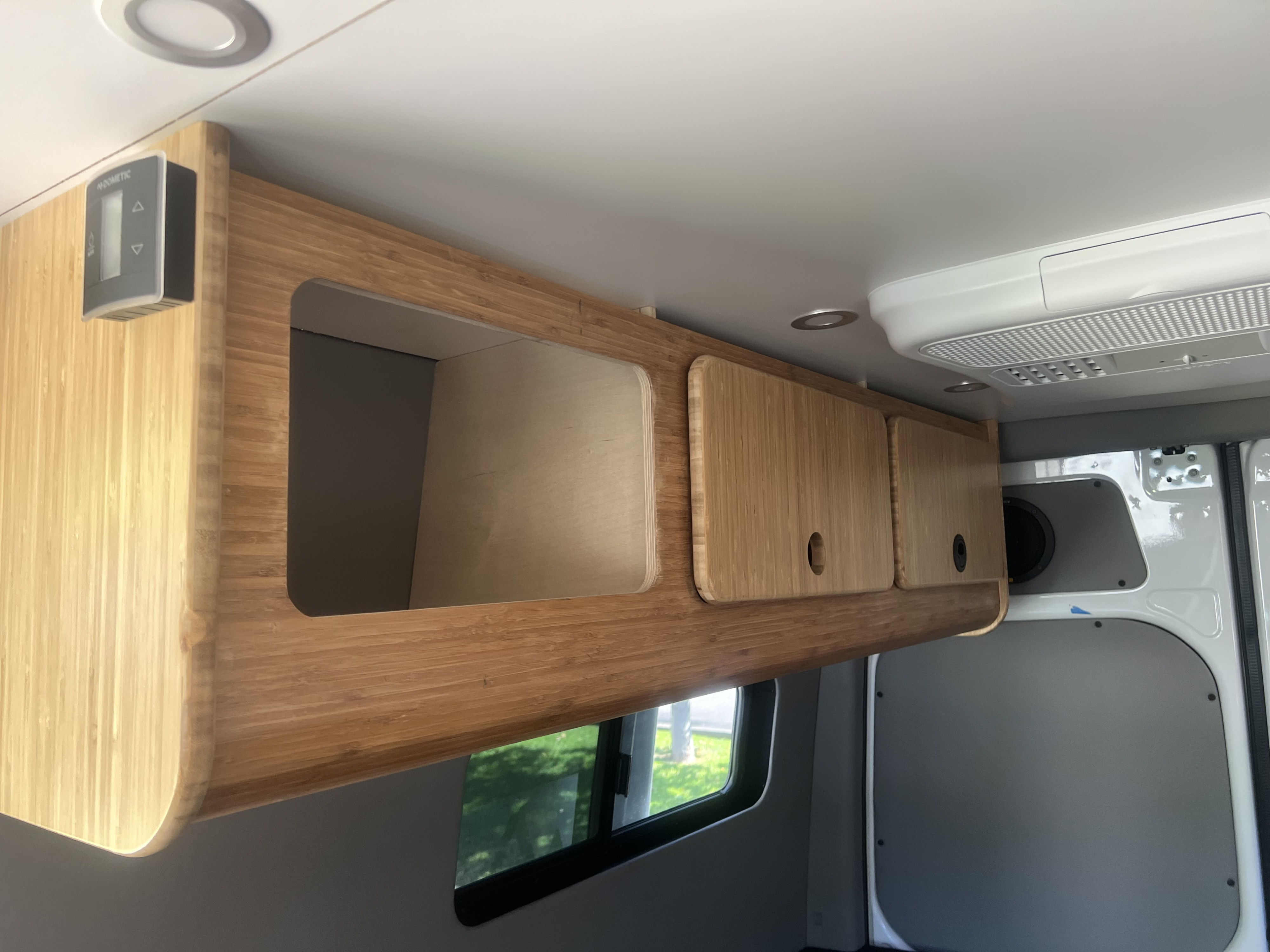 Stylish bamboo overhead storage cabinets with a Dometic control panel on the left, visible in this RV rental's interior.. Mercedes Sprinter Sprinter 2500 2021