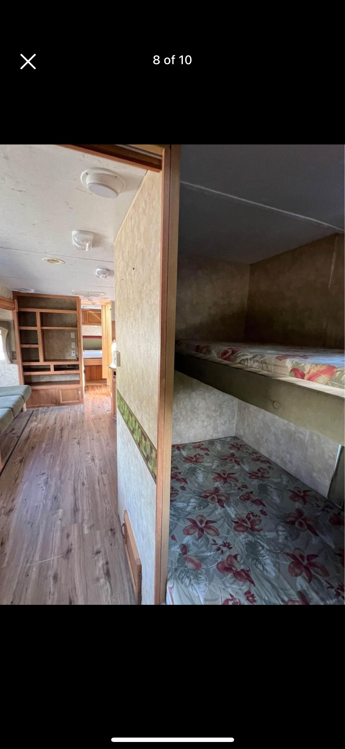 Inside an RV rental, showing a cozy living area with wood-look flooring, built-in shelves, and bunk beds.. Jayco Jay Flight 2007