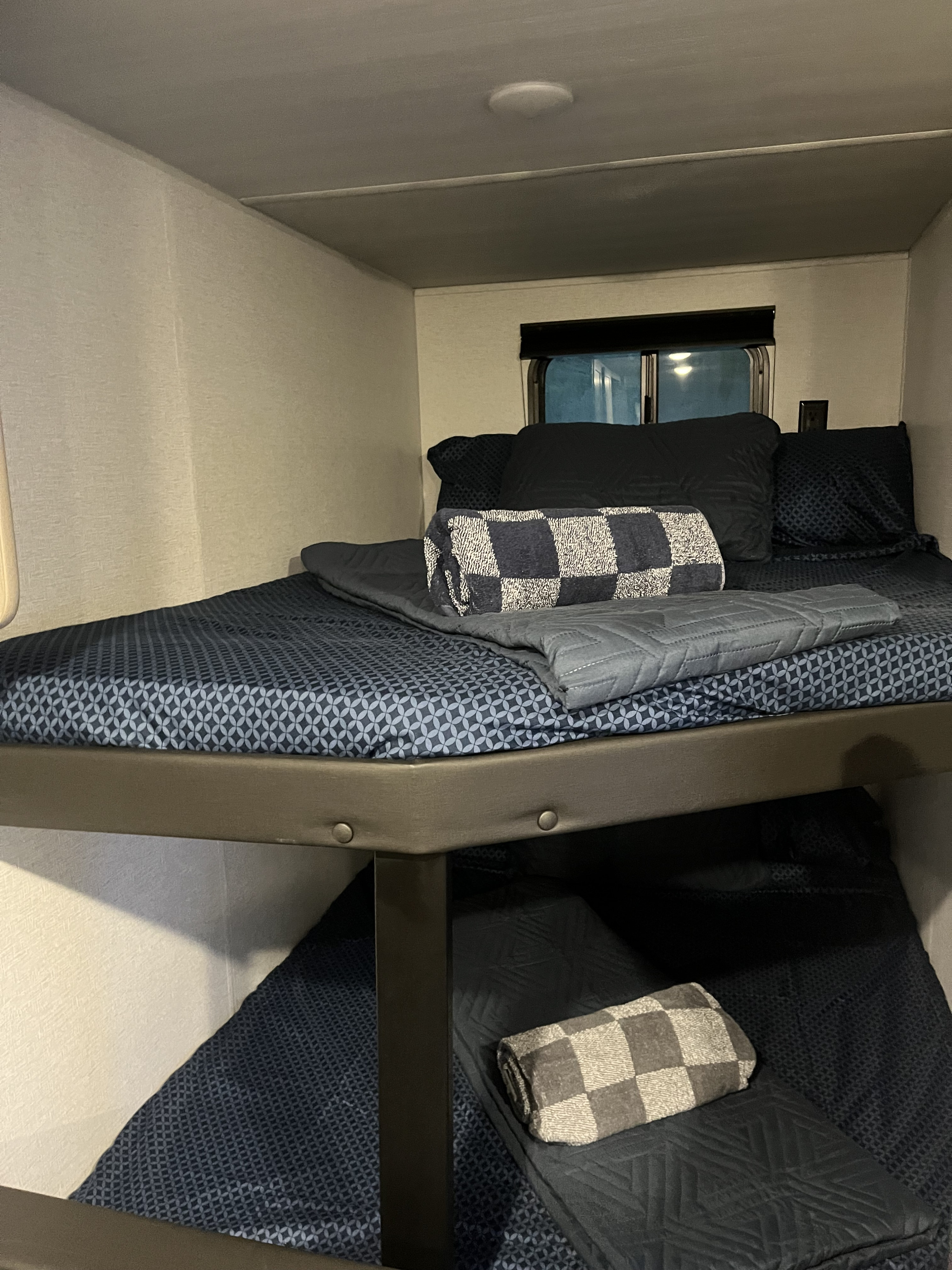 Cozy bunk beds in an RV rental, featuring patterned bedding and blankets, offer comfortable sleeping for travelers.. Keystone RV Springdale 2024