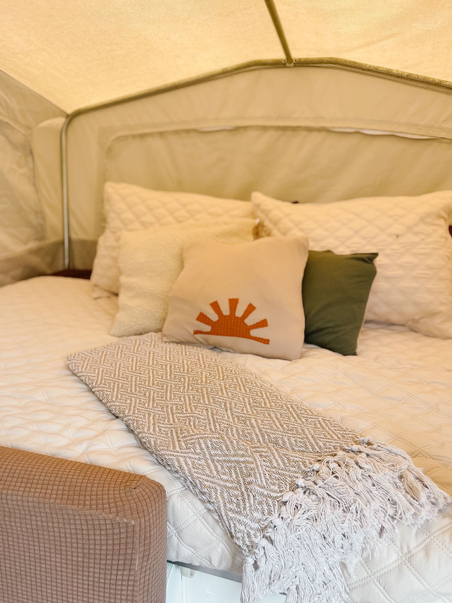 RV rental comfort: A cozy bed with soft pillows, quilted bedding, sun accent, and a decorative throw.. Starcraft Camping Trailers 1995