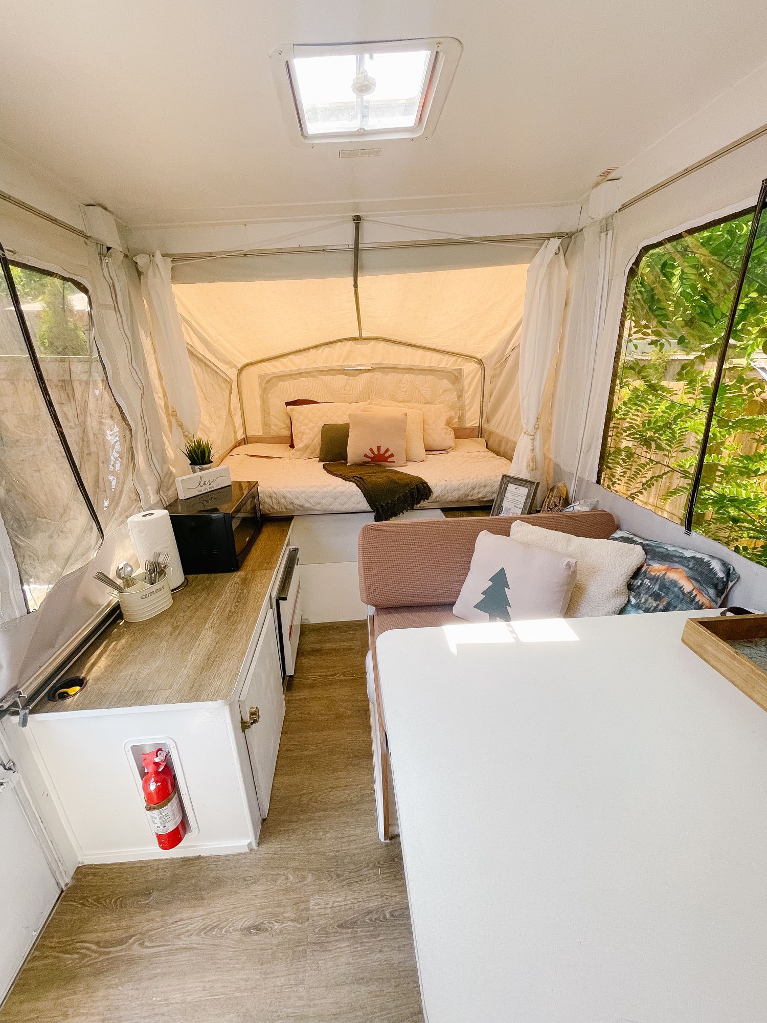 Bright and cozy pop-up camper interior featuring a bed, dining nook, and kitchenette, ready for your RV rental.. Starcraft Camping Trailers 1995