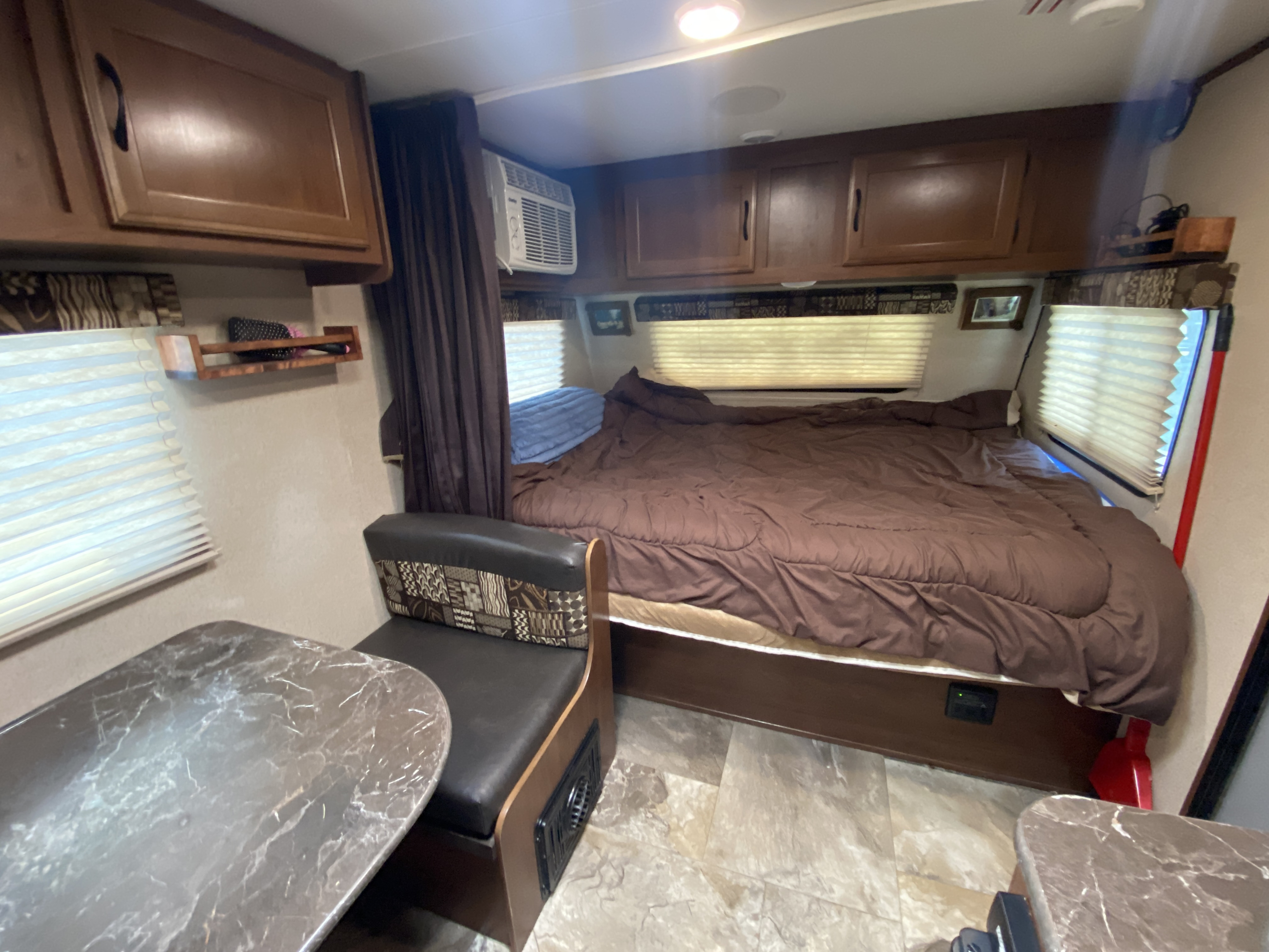 Cozy rv rental interior featuring a neatly made bed, dinette, and overhead cabinets. Ideal for travel.. Jayco Jay Flight SLX 2016
