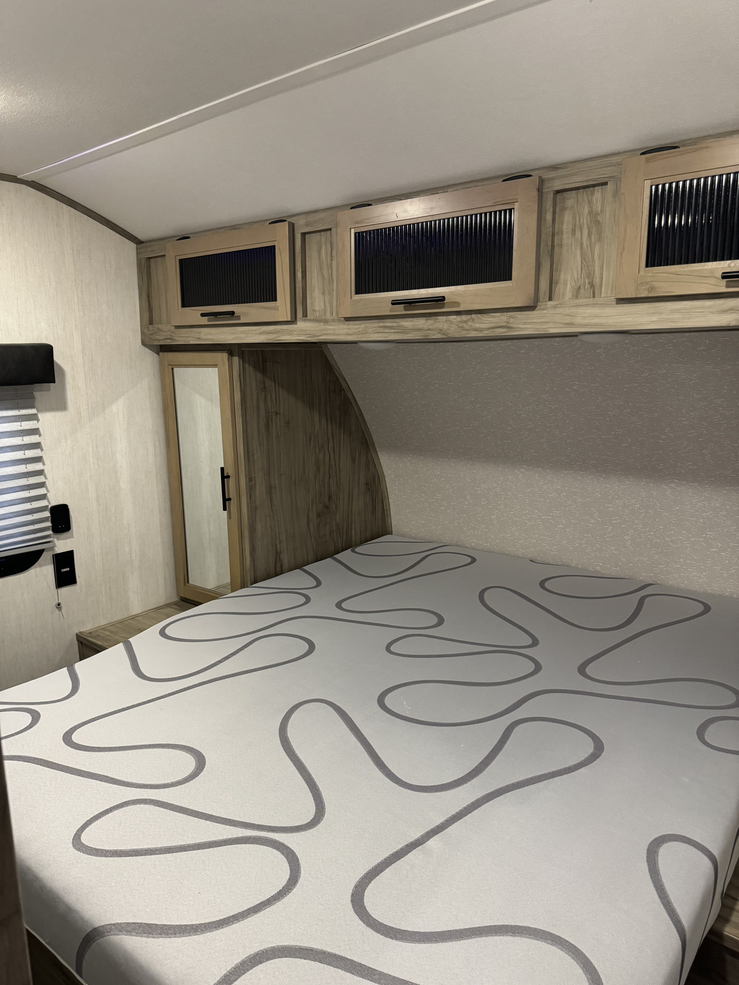 Spacious RV rental bedroom with a comfy bed, modern overhead cabinets, and a convenient mirrored wardrobe. Perfect for your next adventure.. Forest River Cherokee Alpha Wolf 2021