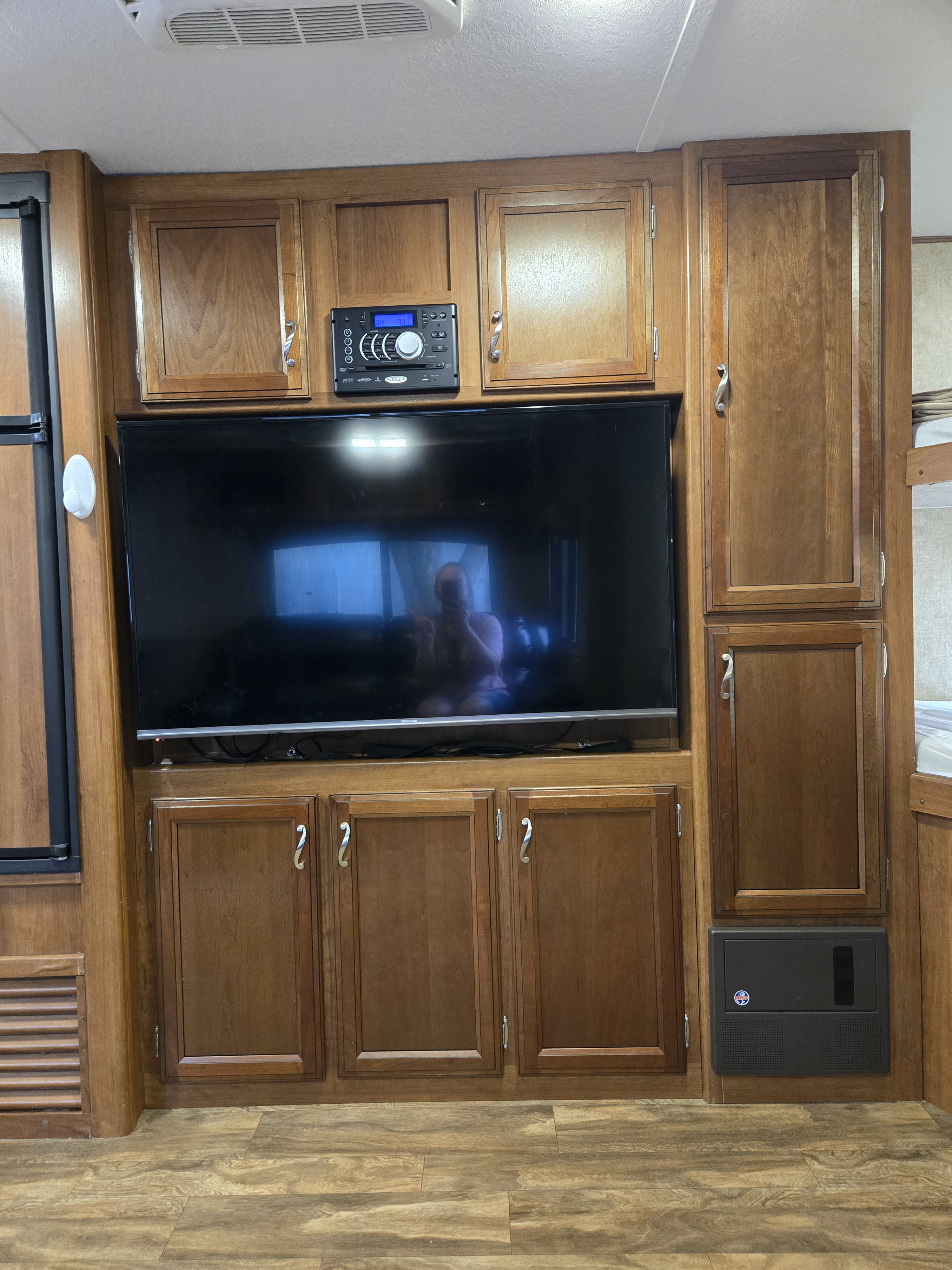 RV rental living space showing TV, stereo, fridge, wood cabinets, and bunk bed.. Avenger ATI 2017