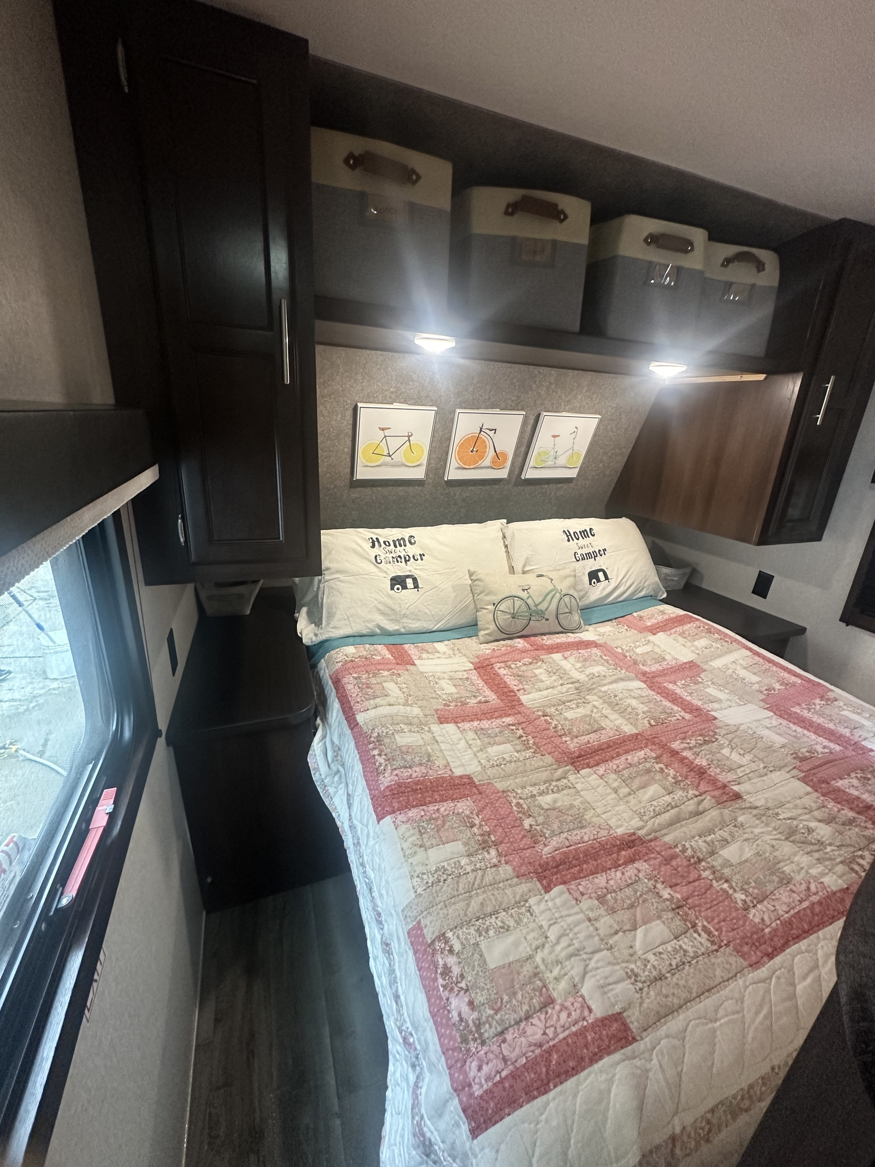 Cozy RV rental bedroom: quilted bed, 'Home Sweet Camper' pillows, fruit-bicycle art, and overhead storage.. Jayco Jay Flight SLX 2019
