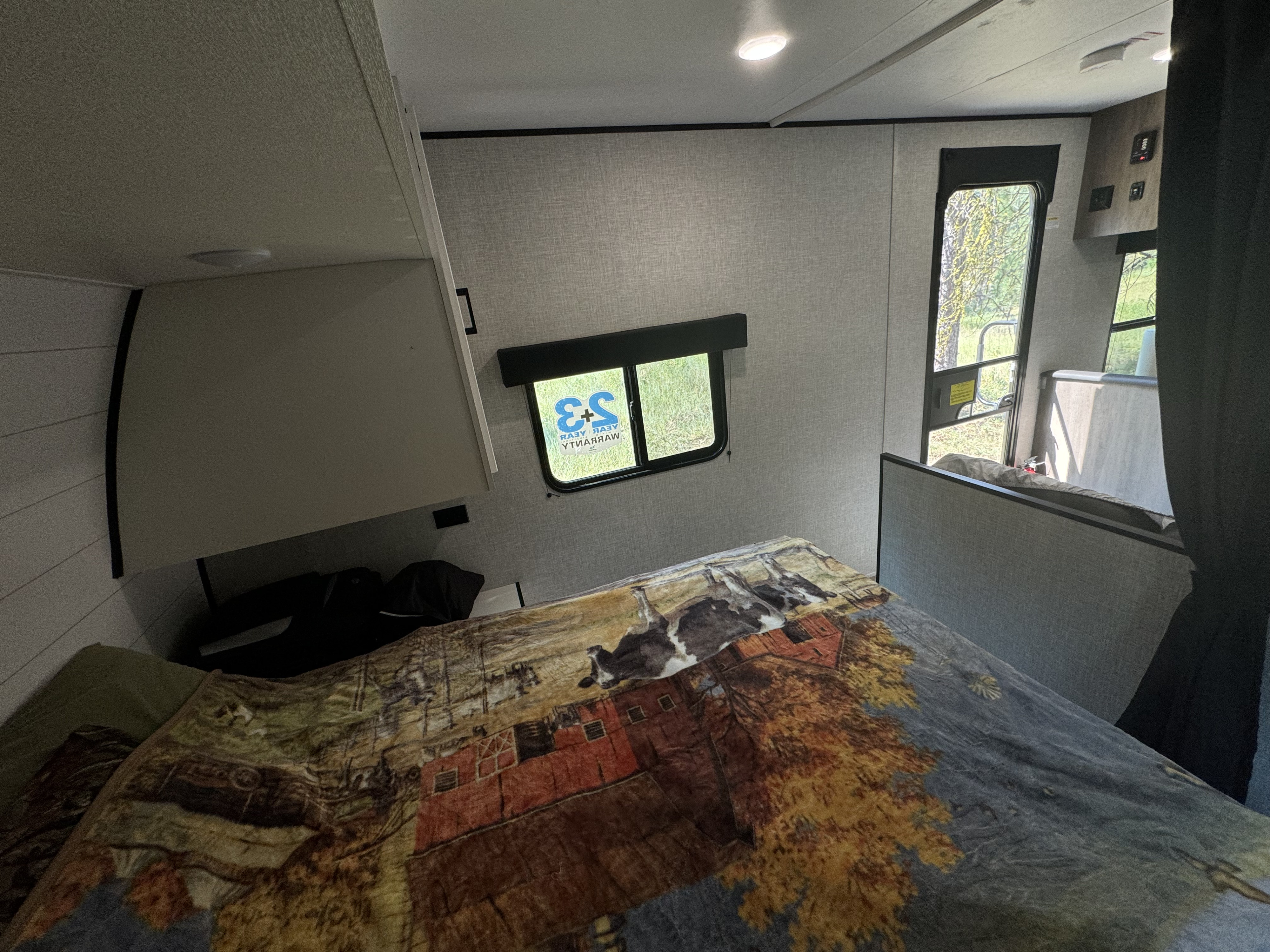 Cozy RV rental bedroom with a comfortable bed, featuring a farm-themed blanket. Natural light filters in from the windows.. Jayco Jay Flight SLX 2024