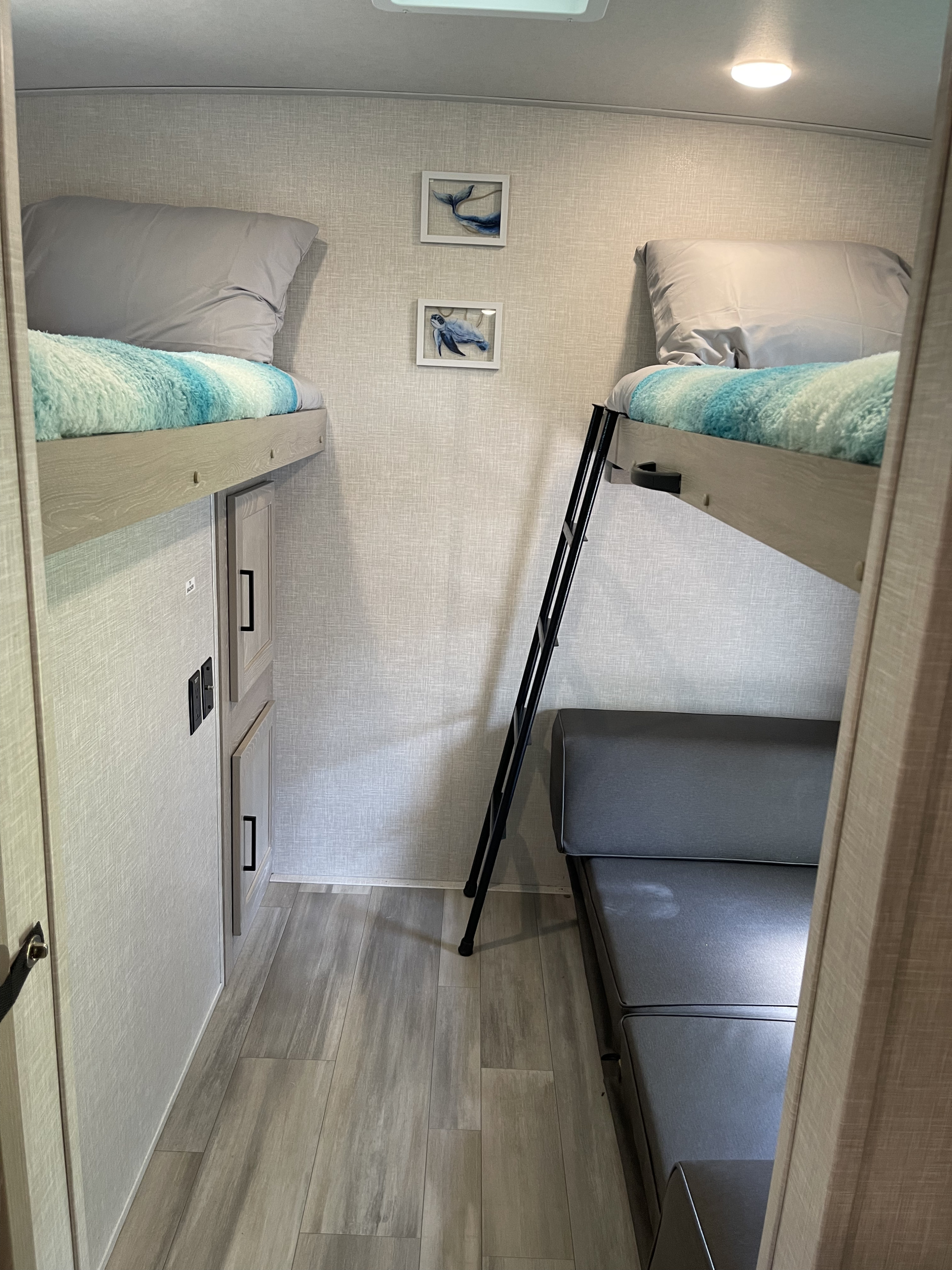 This RV rental features a cozy bunk room with two beds, marine art, and a convertible sofa, maximizing space for travelers.. Forest River Rockwood Ultra Lite 2022