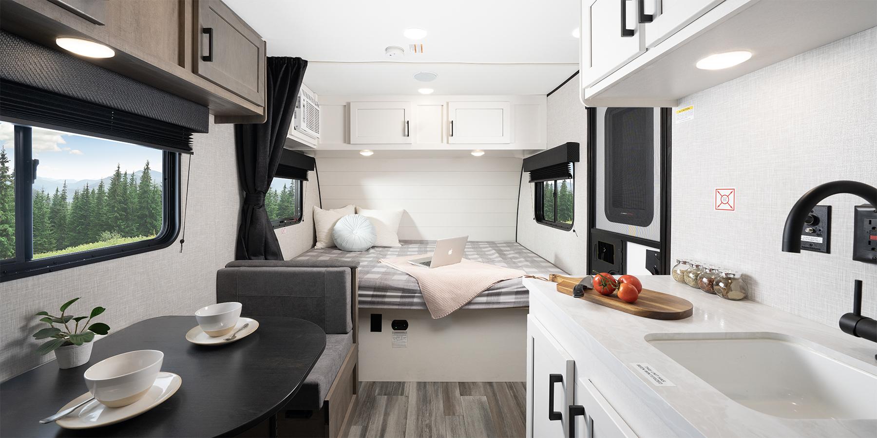 Modern RV rental interior with a dining area, cozy bed, and compact kitchen. Enjoy the views from this comfortable travel trailer.. Jayco Jay Flight SLX 2024