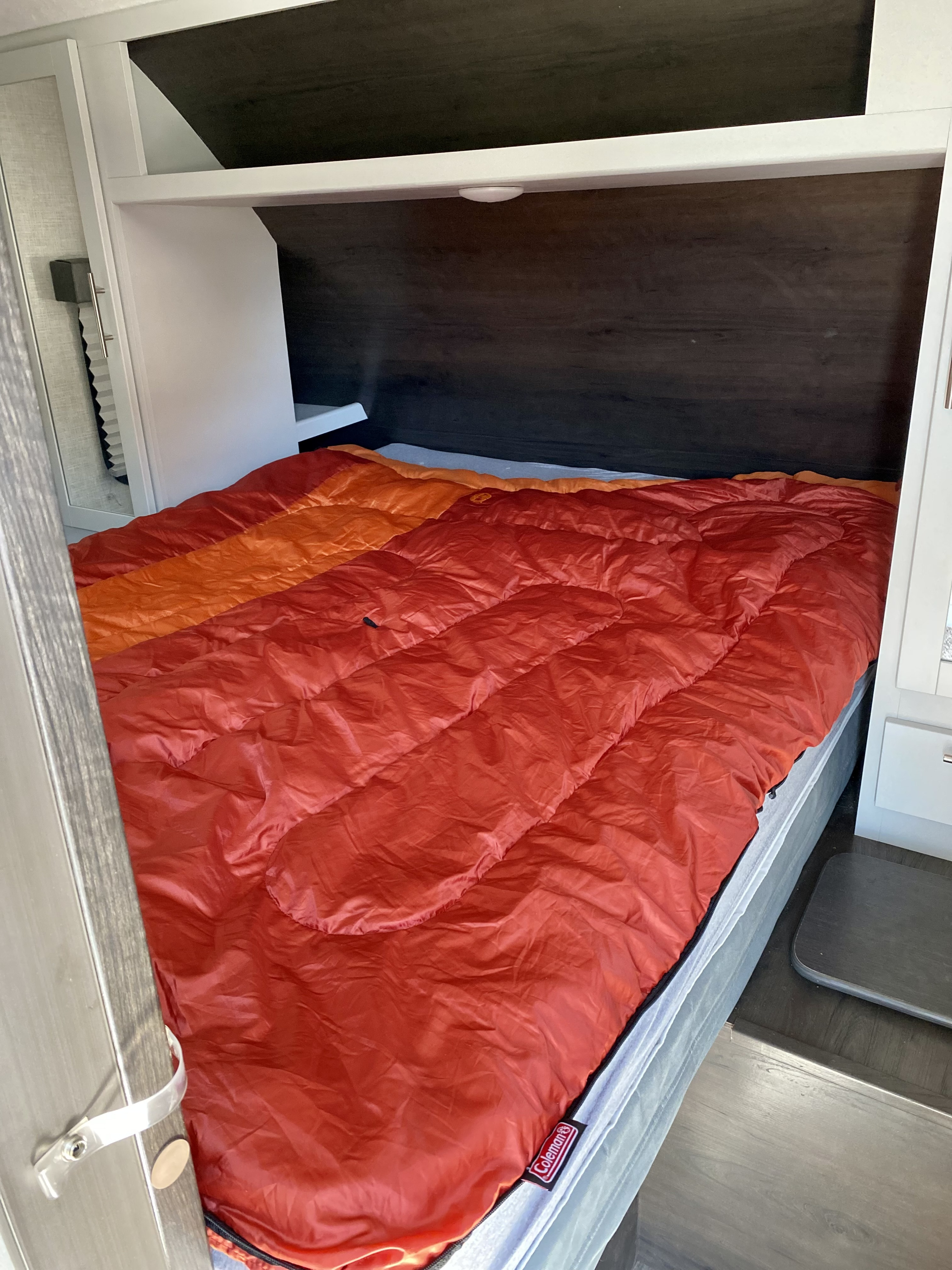 Cozy RV rental bedroom with an inviting orange Coleman sleeping bag on the bed, perfect for your next trip.. Keystone Bullet 2021