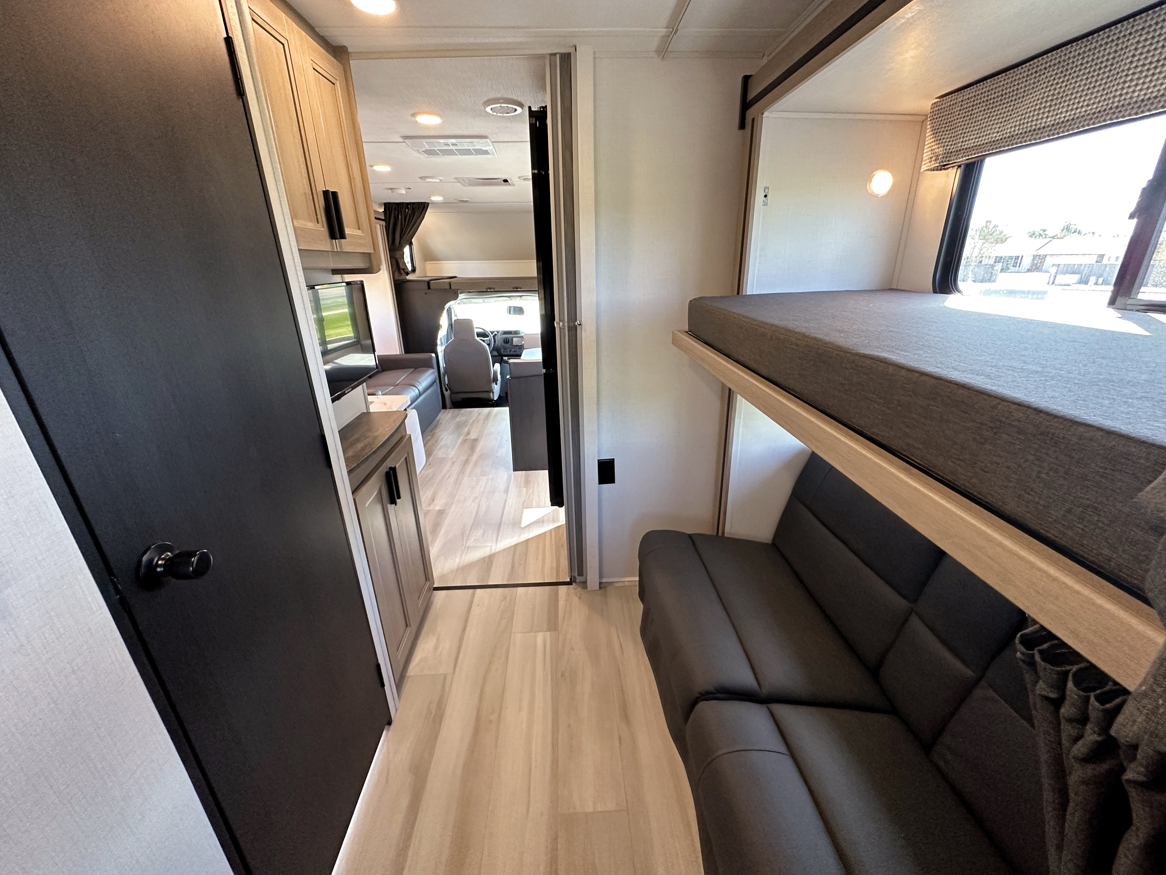 RV rental interior: Bunk beds, compact kitchen, and forward cockpit visible. Bright, modern living space for your journeys.. Forest River Sunseeker 2024