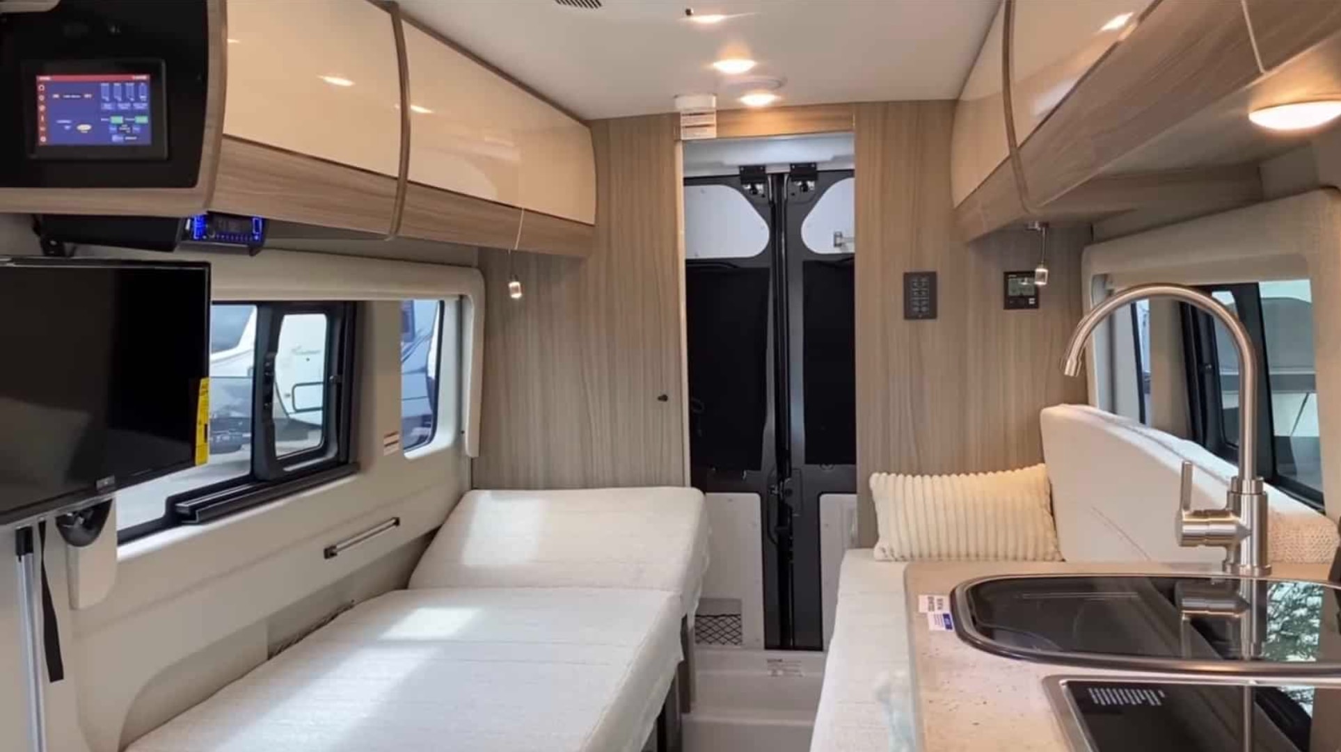 Modern camper van RV rental interior. Features include beds, TV, kitchen sink, and digital controls for comfort.. Jayco Swift 2022