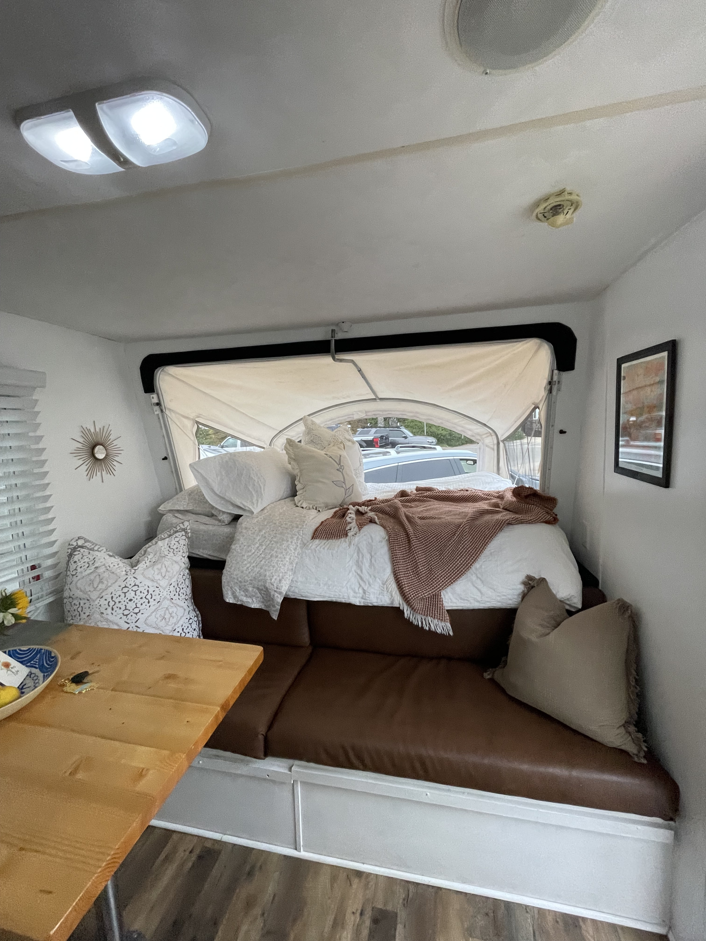 A cozy RV rental interior featuring a pop-up bed, brown sofa, and dining table, ideal for comfortable travel adventures.. Forest River Wildwood 2011