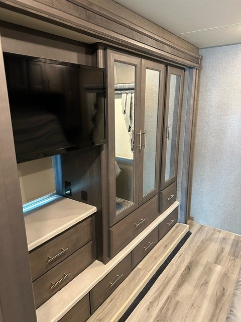 Inside this modern RV rental: built-in TV, wardrobe with mirrored doors, and ample storage for your travels.. Thor Miramar 2022
