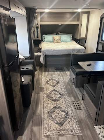RV rental interior: queen bed, dinette, cozy seating, and fridge. Comfort for your next adventure.. Keystone RV Hideout 2024