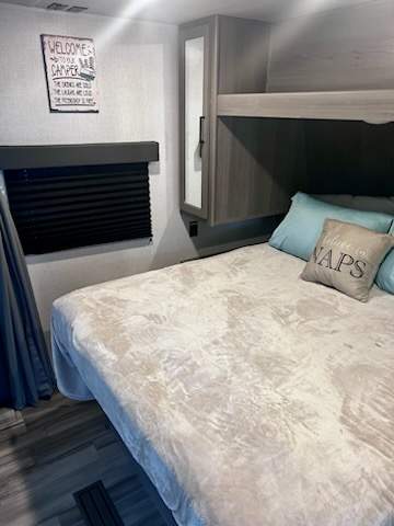 Spacious RV rental bedroom with a cozy bed, bunk, and window. Ideal for comfortable camper getaways.. Keystone RV Hideout 2024