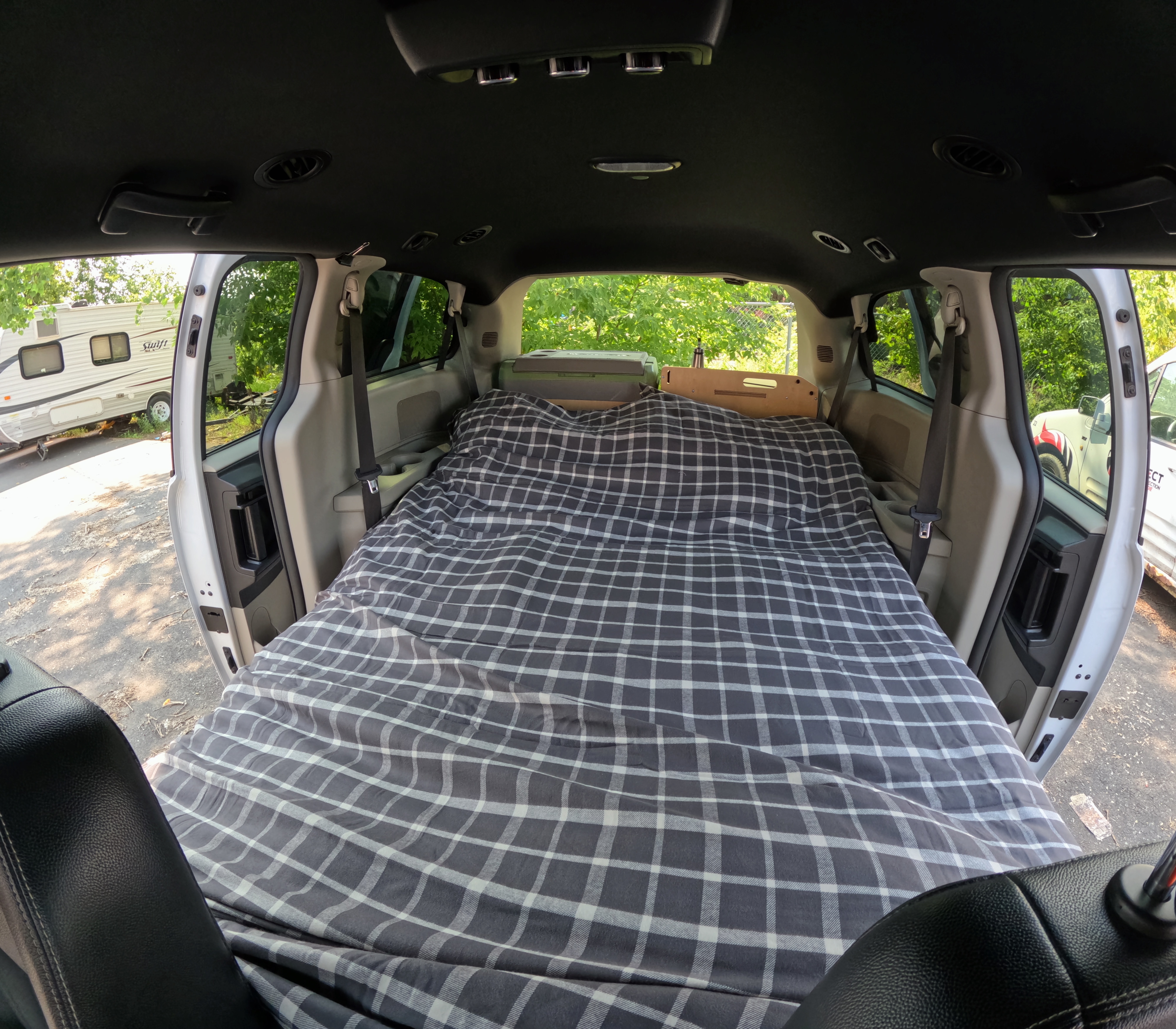Comfortable plaid bed in a converted minivan, ready for an RV rental-style adventure.. Dodge Grand Caravan 2019