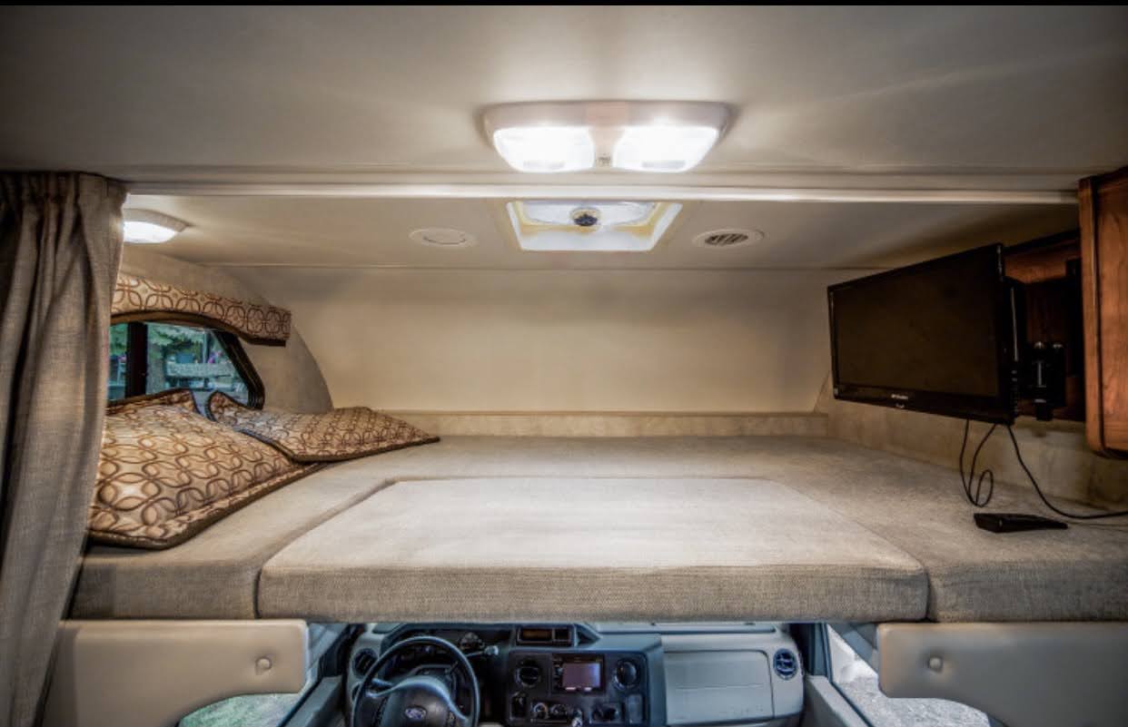 Spacious RV rental cab-over bunk area with comfy bed, TV, and window. Ideal for travel comfort.. Other Four Winds 2013